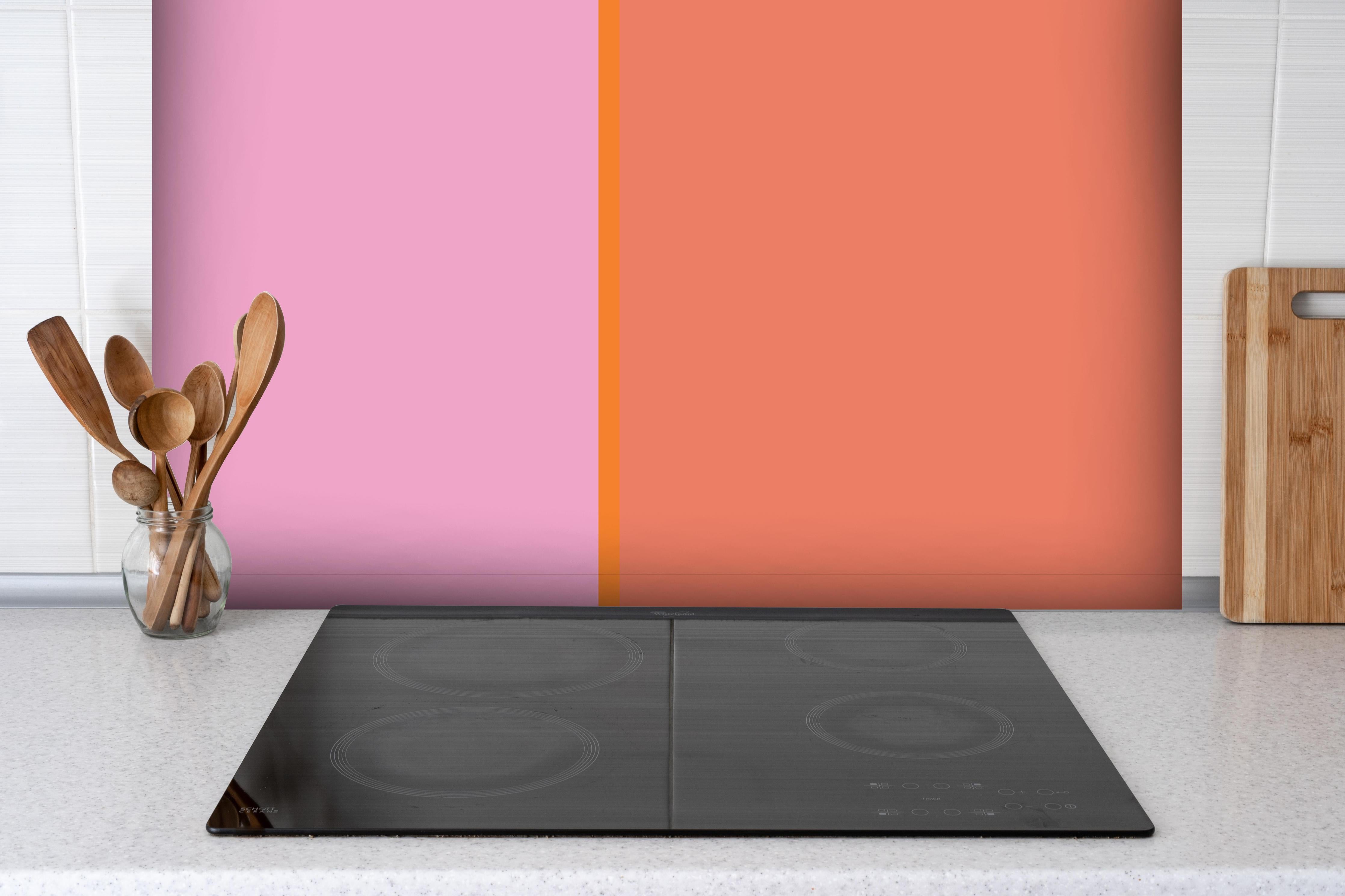 Spritzschutz - The Oranges - Easy Vertical - Coral hinter einem Cerankochfeld zwischen Holz-Kochutensilien