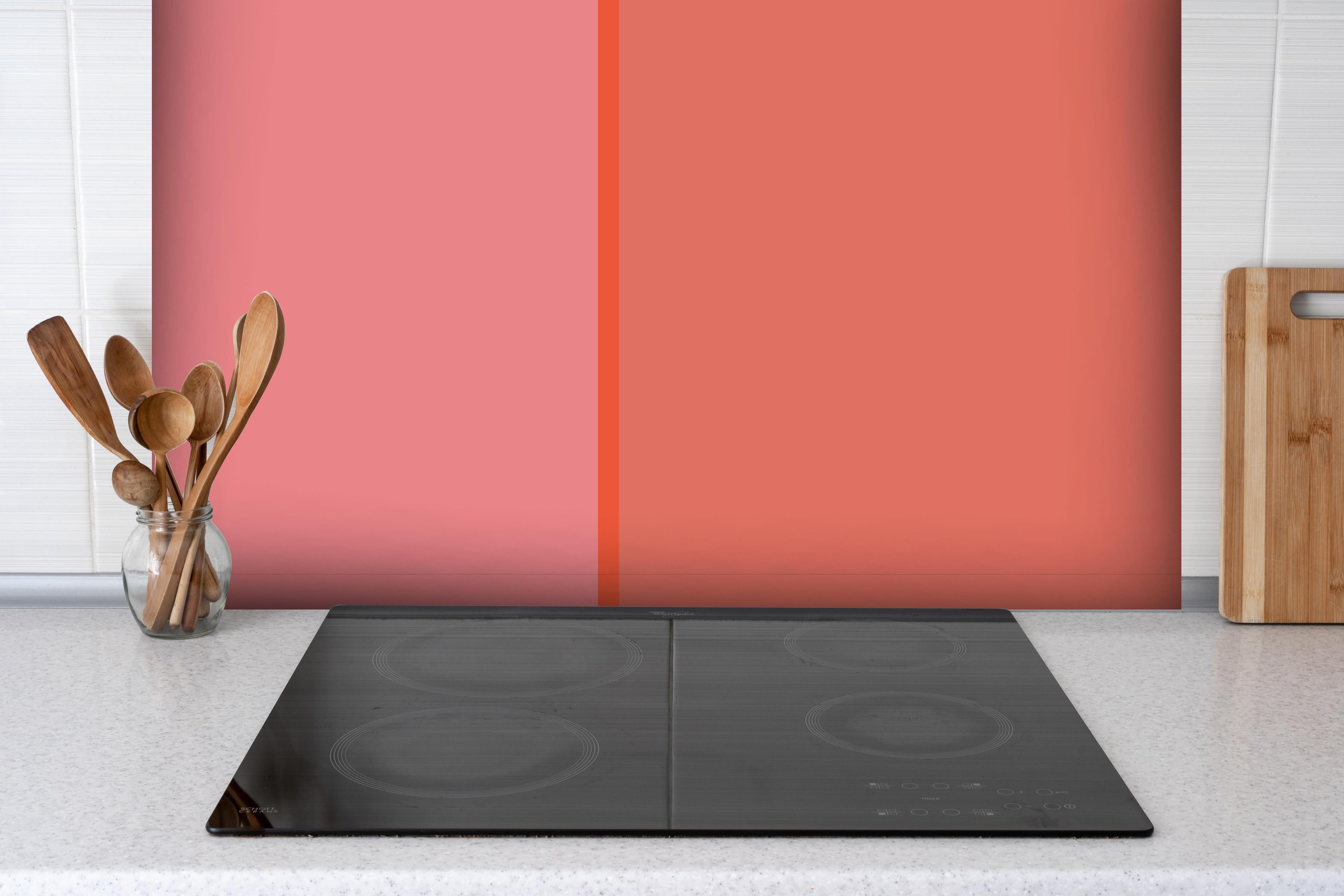 Spritzschutz - The Oranges - Easy Vertical - Salmon hinter einem Cerankochfeld zwischen Holz-Kochutensilien
