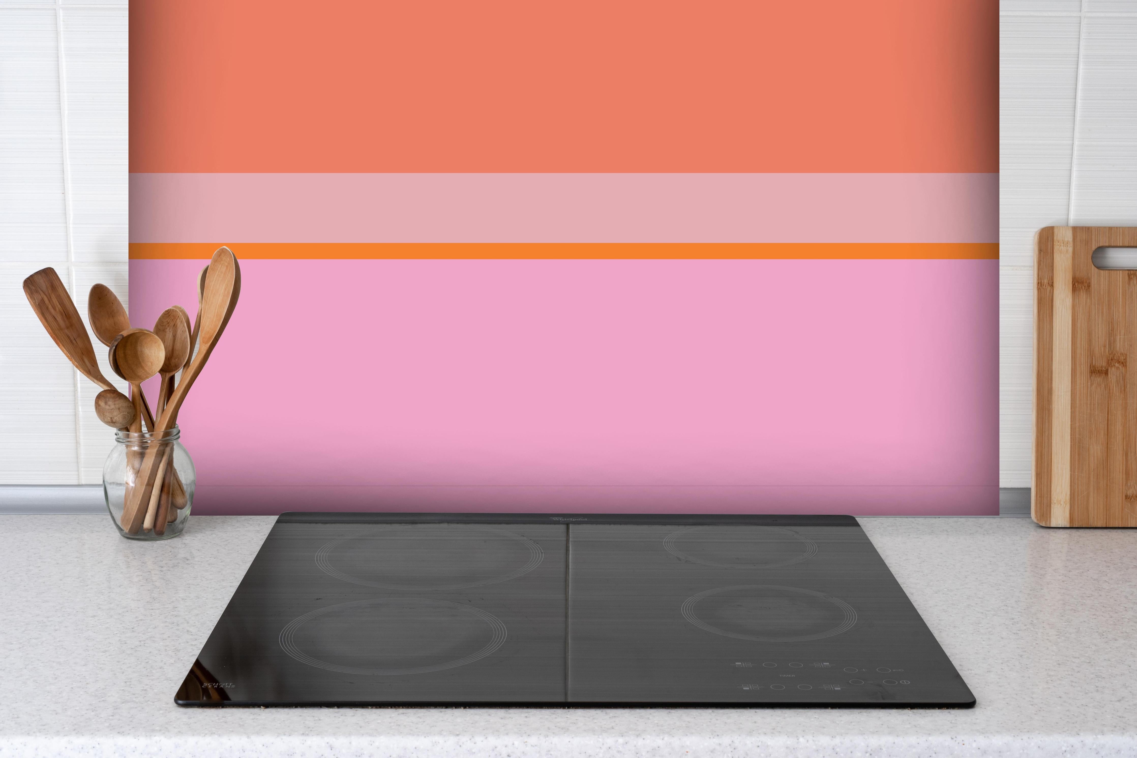 Spritzschutz - The Oranges - Horizontal - Coral hinter einem Cerankochfeld zwischen Holz-Kochutensilien