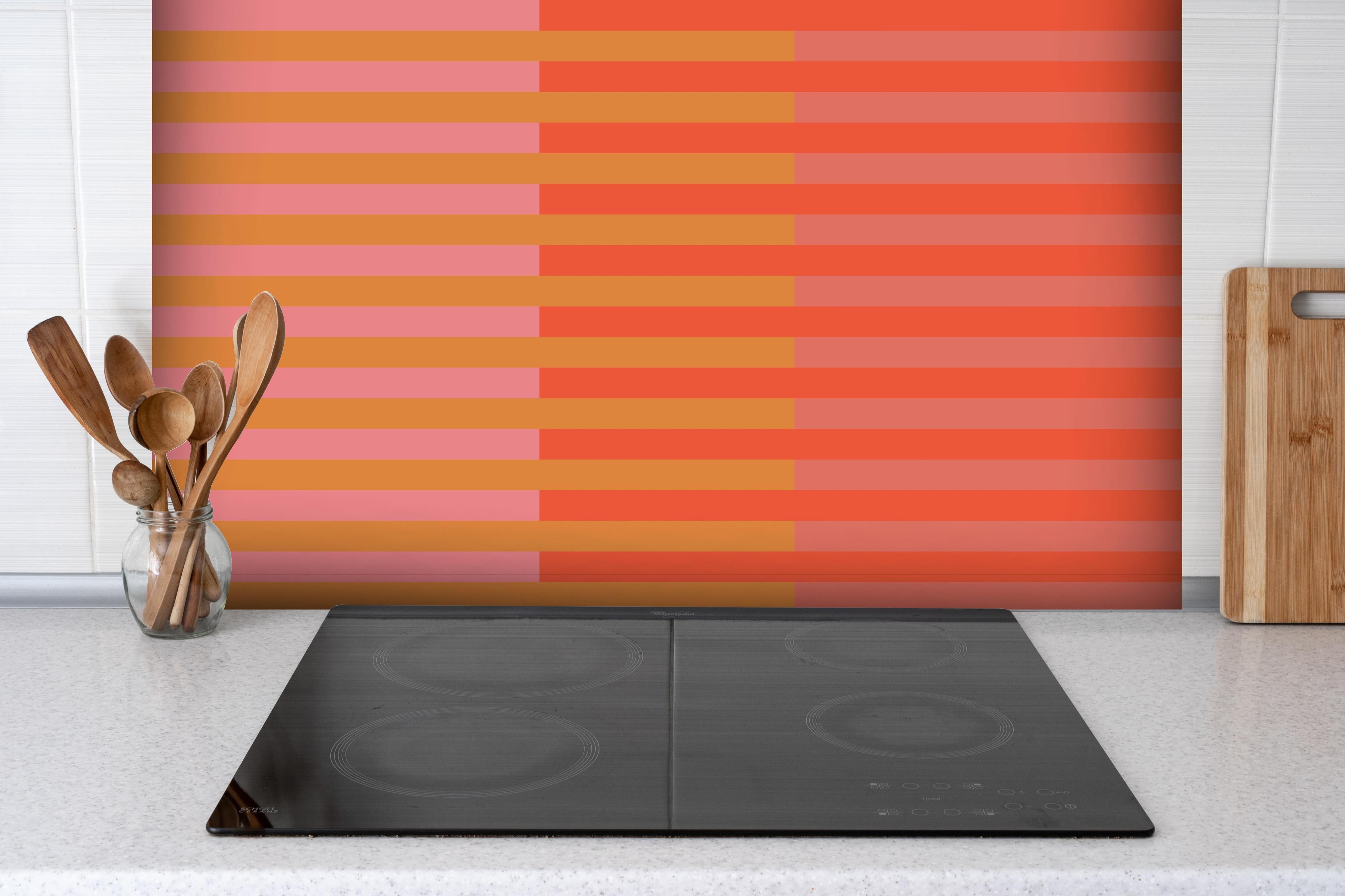 Spritzschutz - The Oranges - Multy Stripes - Salmon hinter einem Cerankochfeld zwischen Holz-Kochutensilien