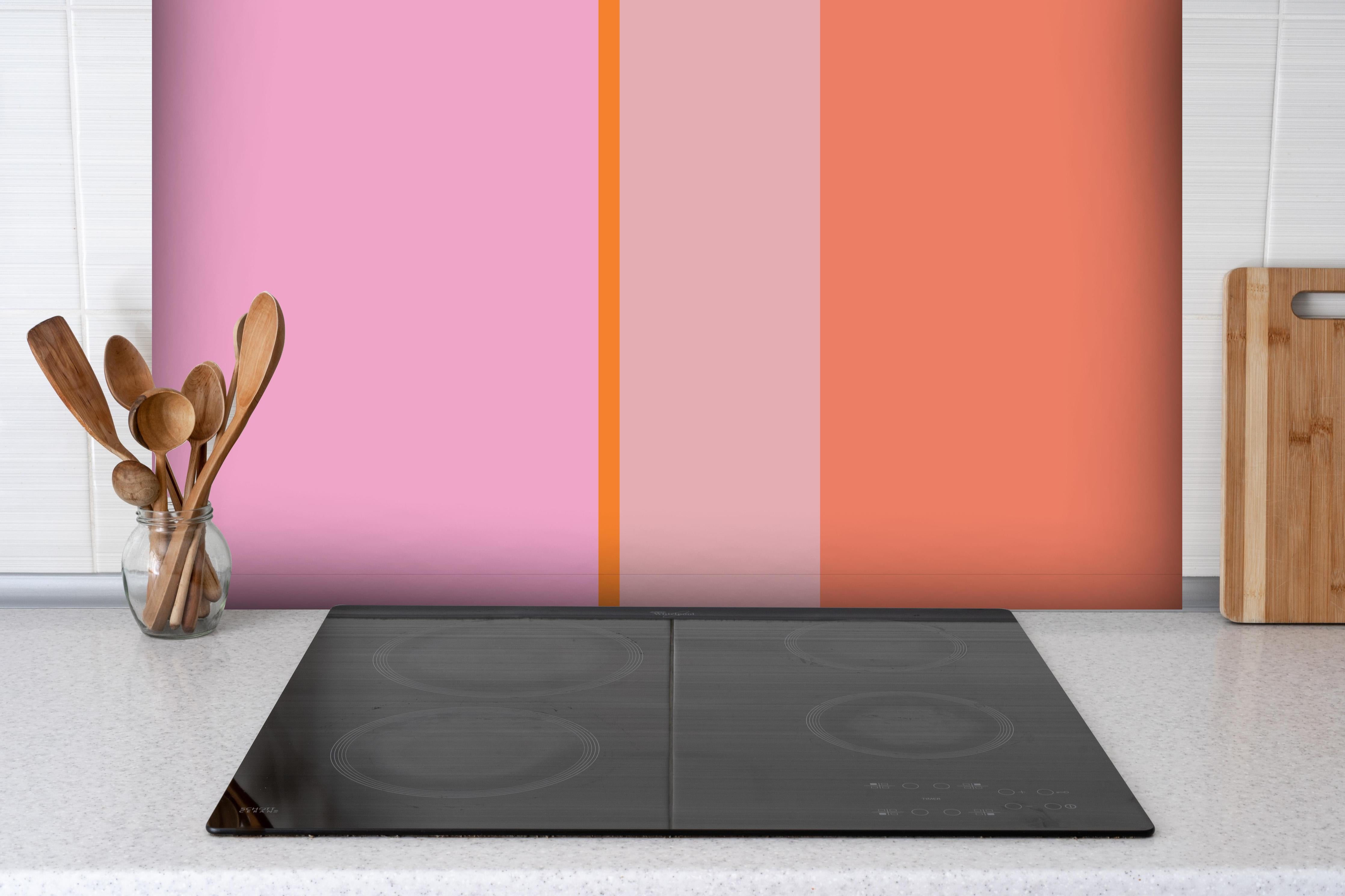 Spritzschutz - The Oranges - Vertical - Coral hinter einem Cerankochfeld zwischen Holz-Kochutensilien