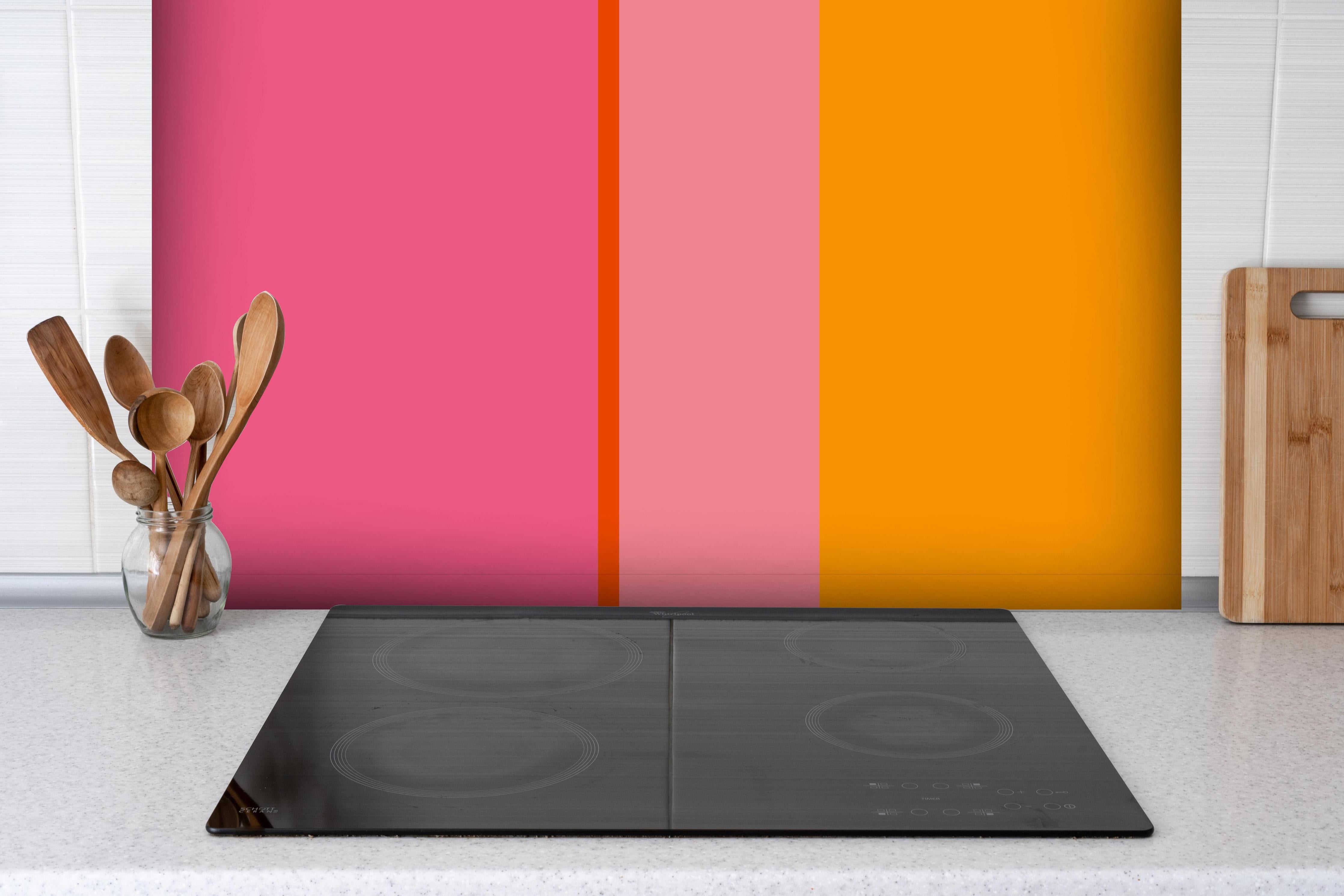 Spritzschutz - The Oranges - Vertical - Raspberry hinter einem Cerankochfeld zwischen Holz-Kochutensilien
