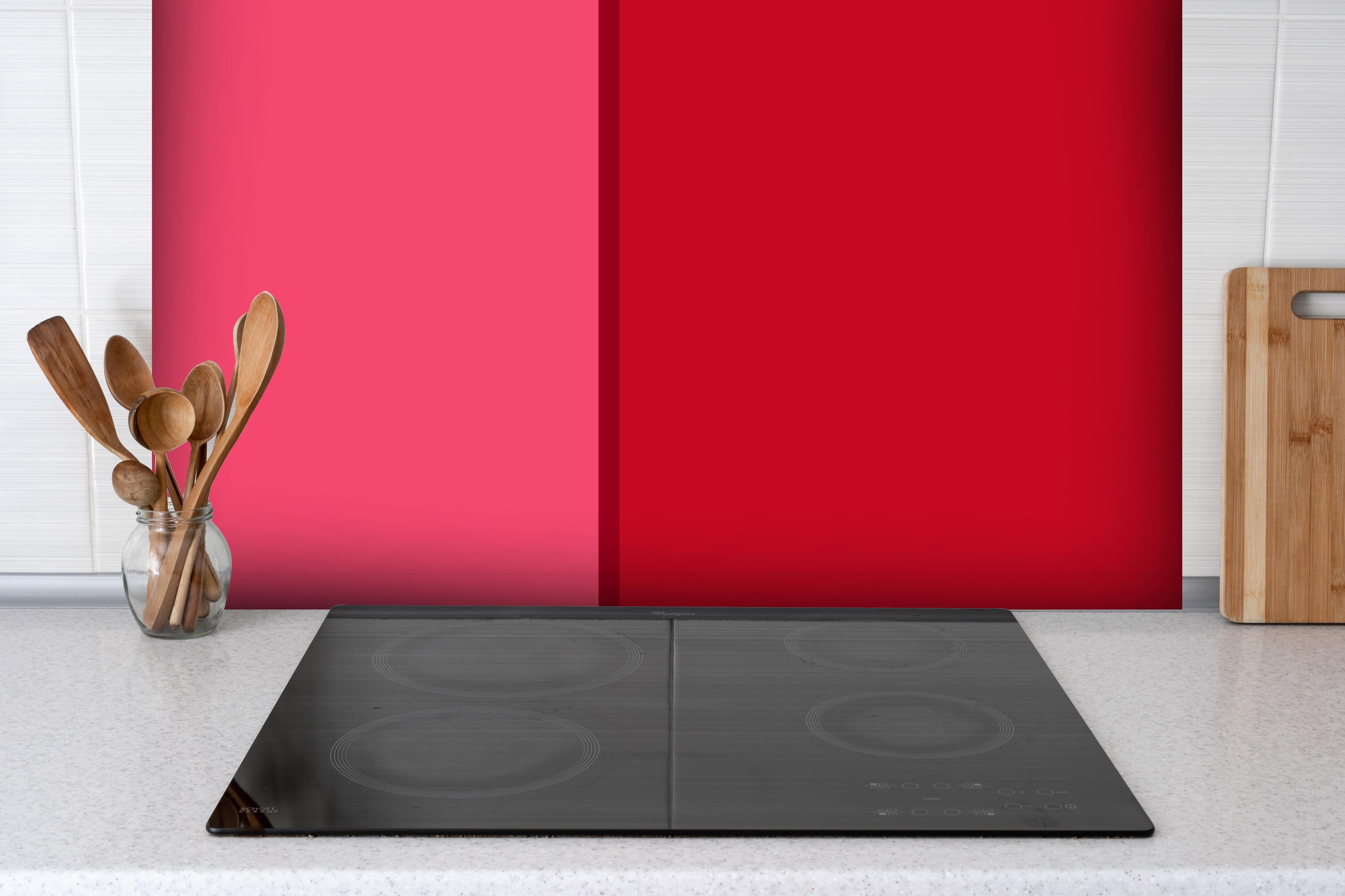 Spritzschutz - The Reds - Easy Vertikal - Pommagranate hinter einem Cerankochfeld zwischen Holz-Kochutensilien