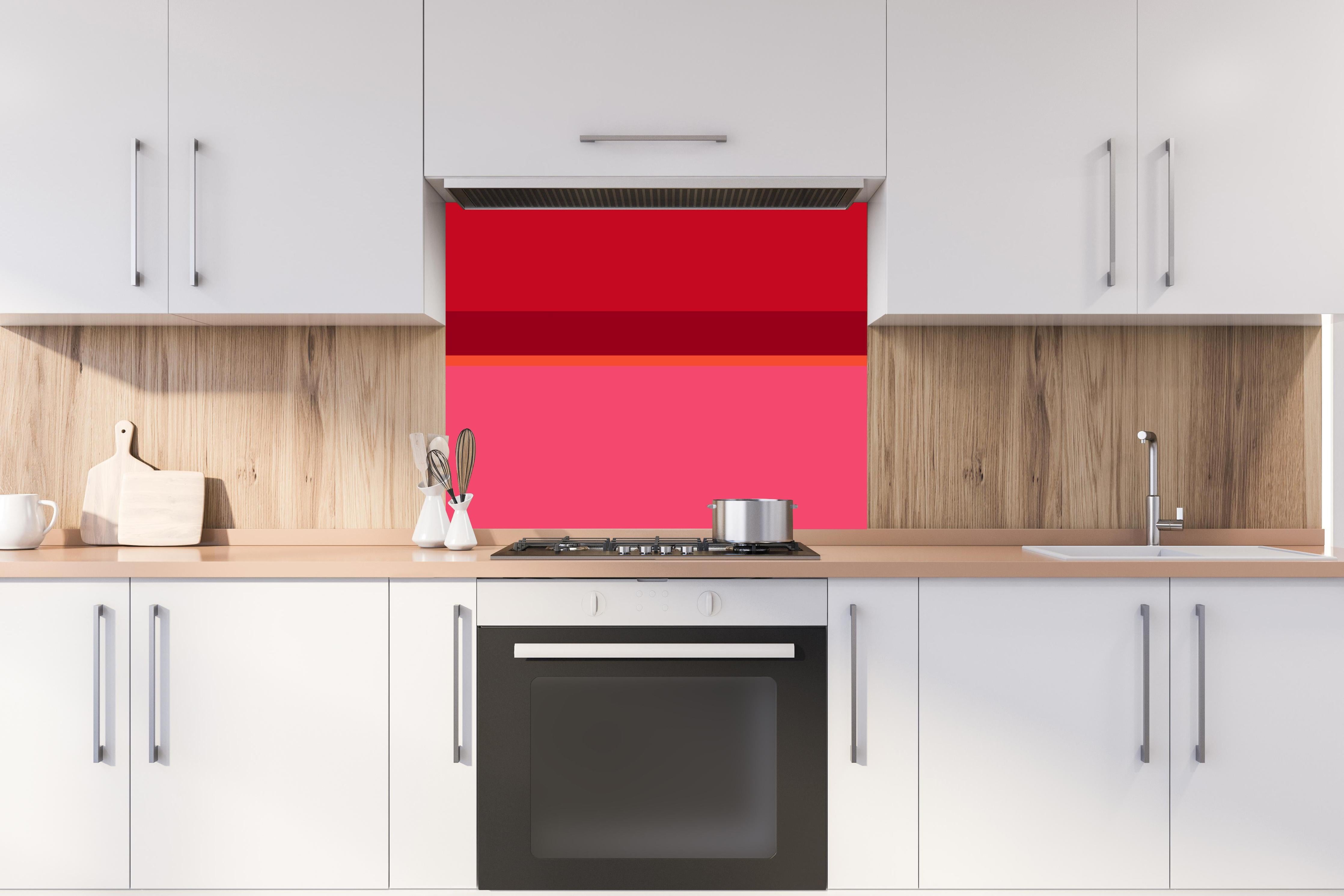Spritzschutz - The Reds - Horizontal - Pommagranate hinter einem Cerankochfeld zwischen Holz-Kochutensilien