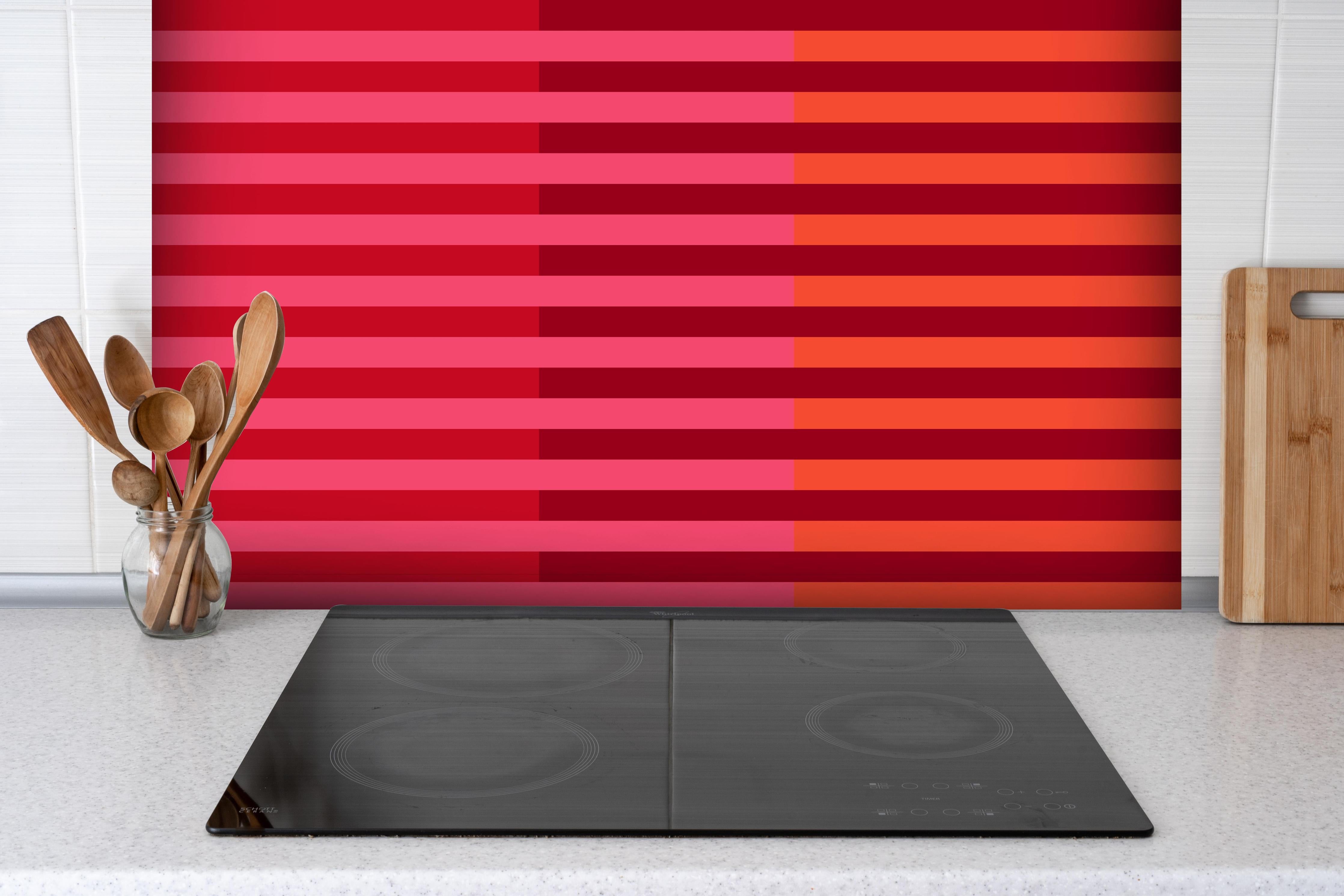 Spritzschutz - The Reds - Multy Stripes - Pomegranate hinter einem Cerankochfeld zwischen Holz-Kochutensilien