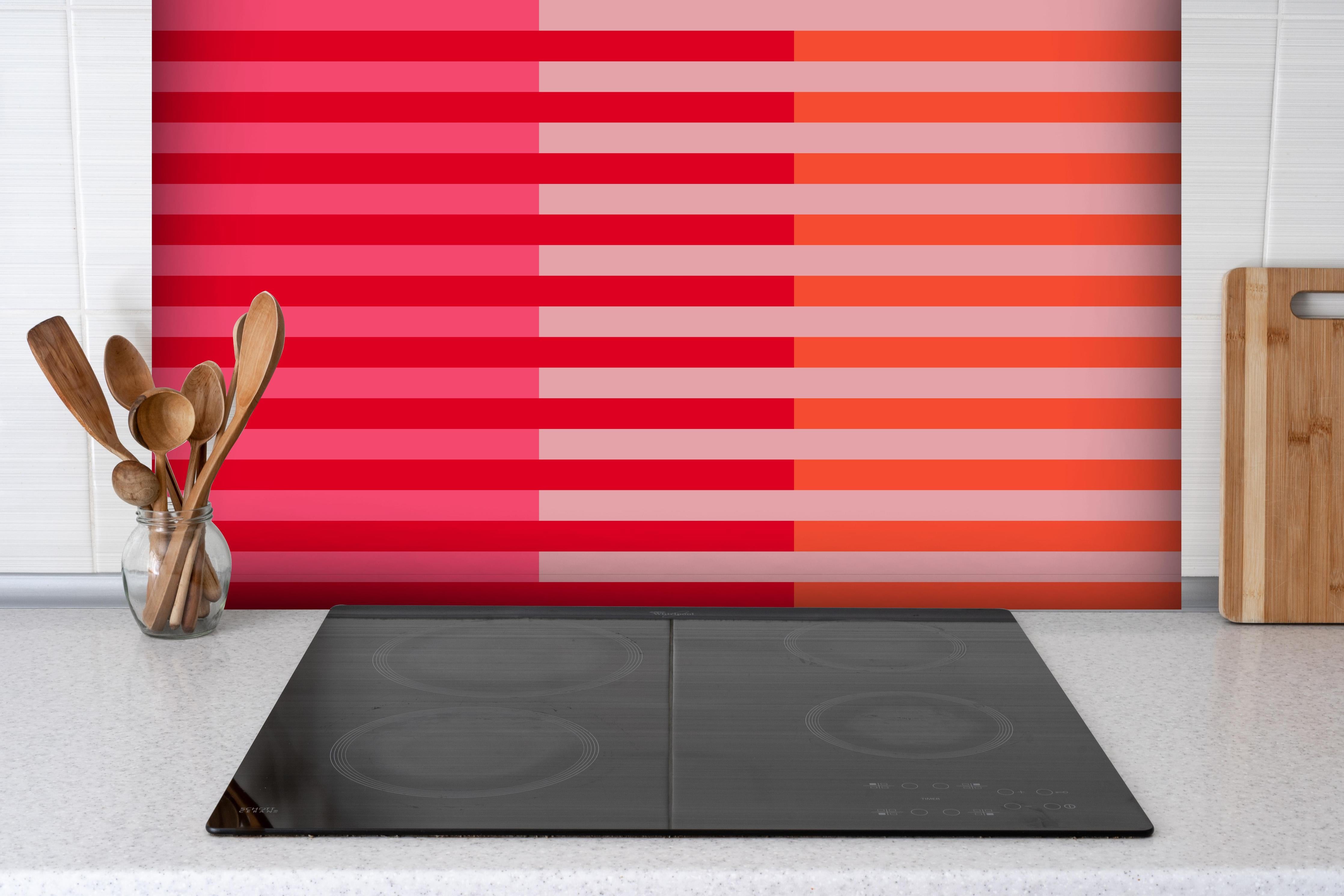 Spritzschutz - The Reds - Multy Stripes - Strawberry hinter einem Cerankochfeld zwischen Holz-Kochutensilien
