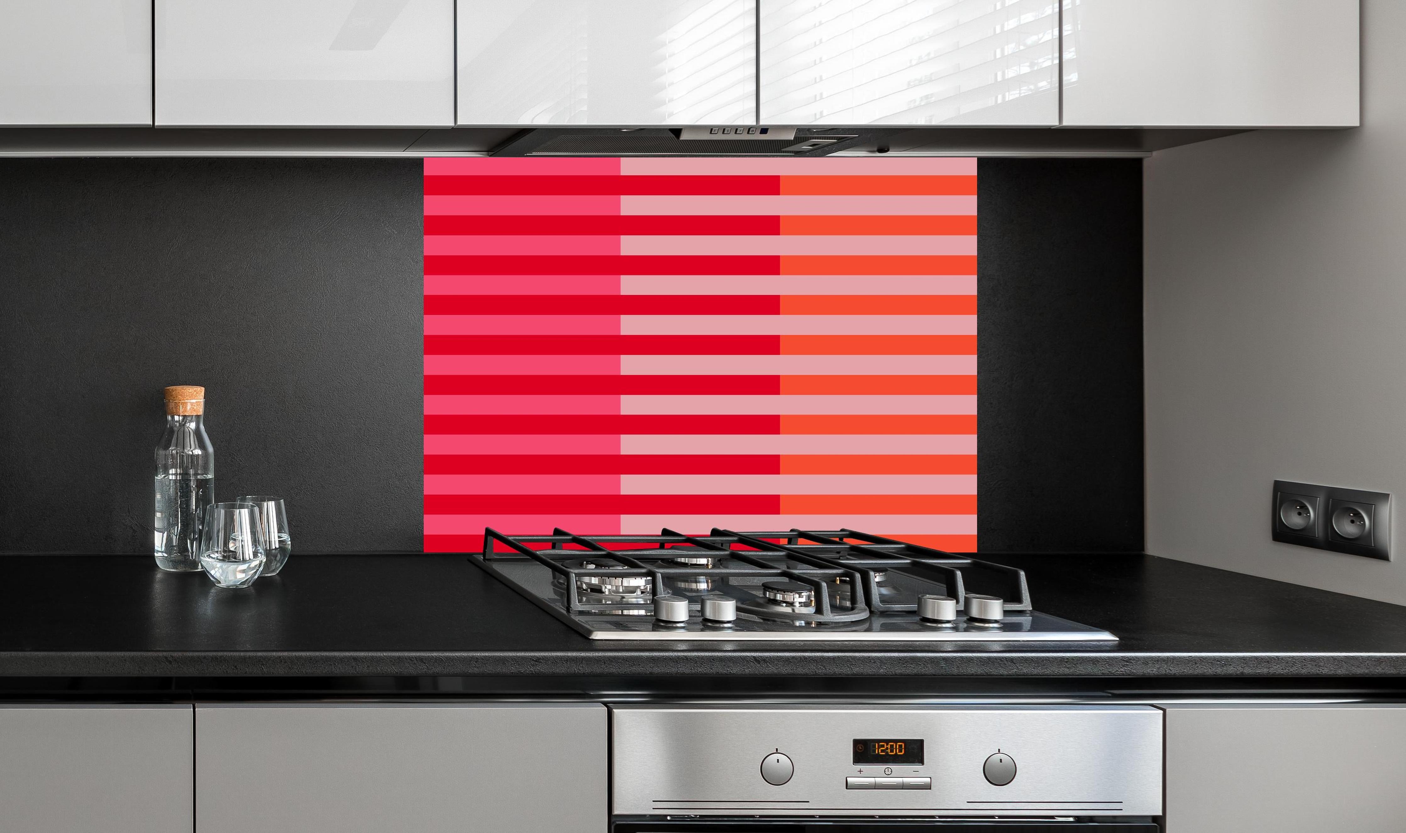 Spritzschutz - The Reds - Multy Stripes - Strawberry hinter einem Cerankochfeld zwischen Holz-Kochutensilien