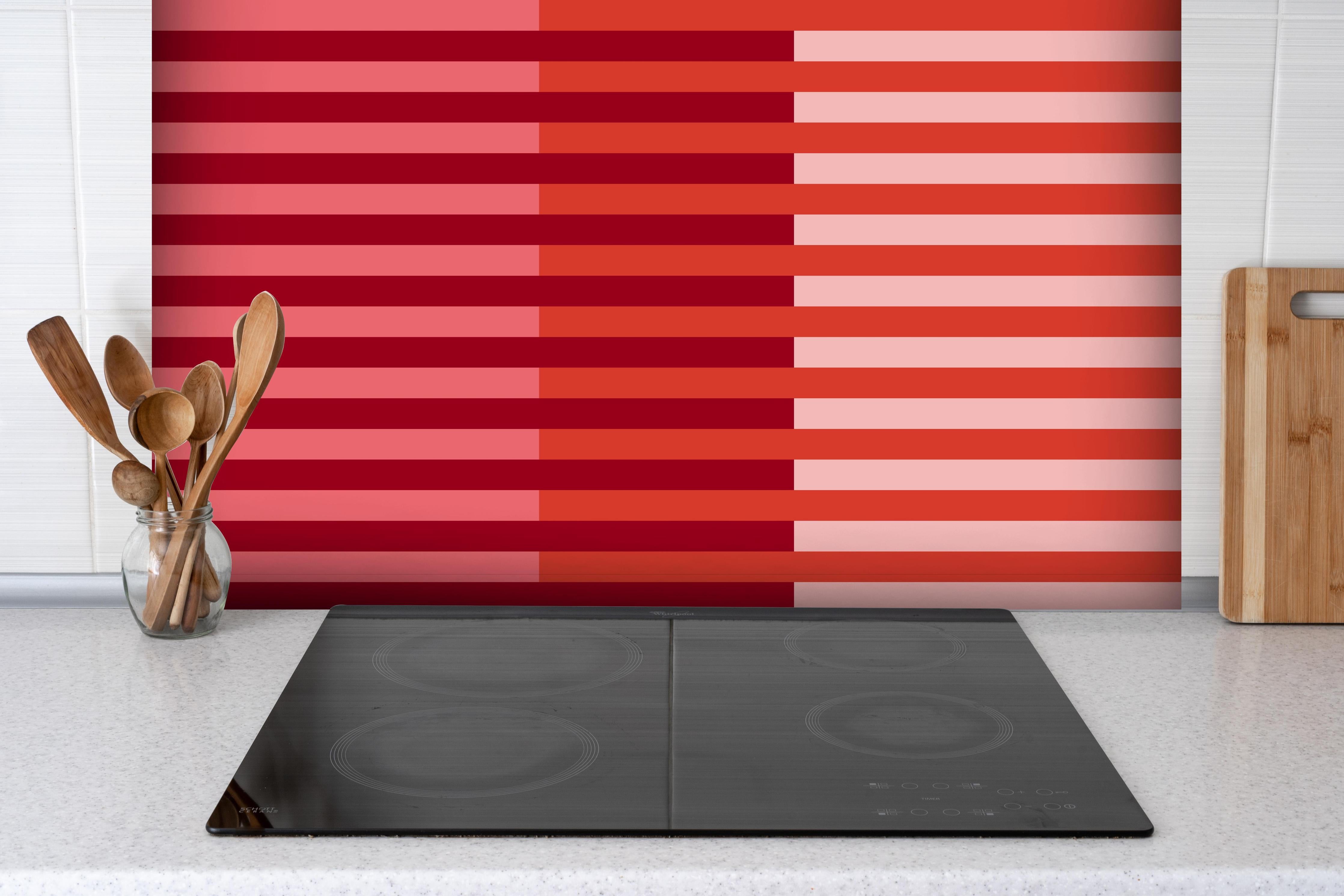 Spritzschutz - The Reds - Multy Stripes - Tomato hinter einem Cerankochfeld zwischen Holz-Kochutensilien
