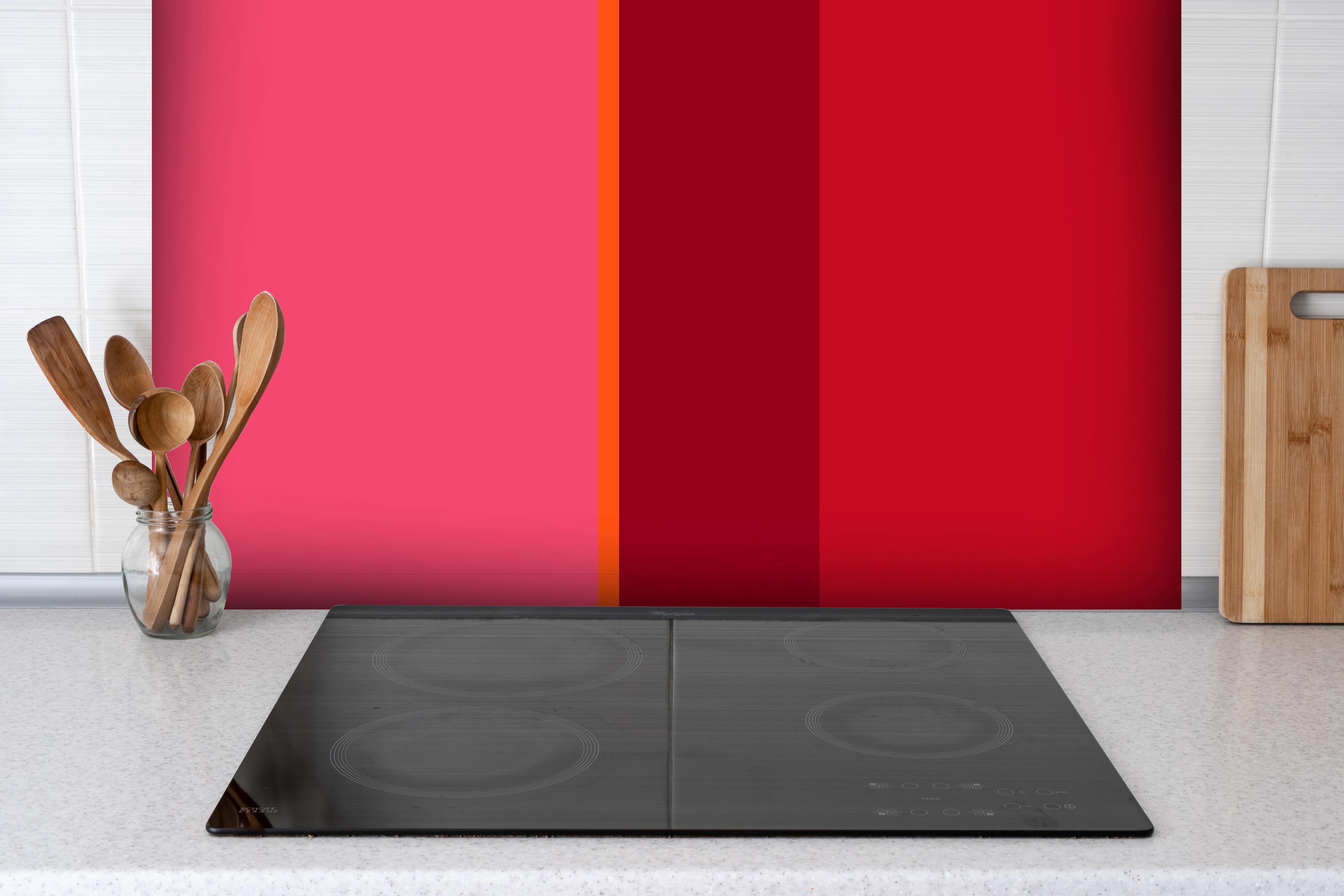 Spritzschutz - The Reds - Vertical - Pommagranate hinter einem Cerankochfeld zwischen Holz-Kochutensilien