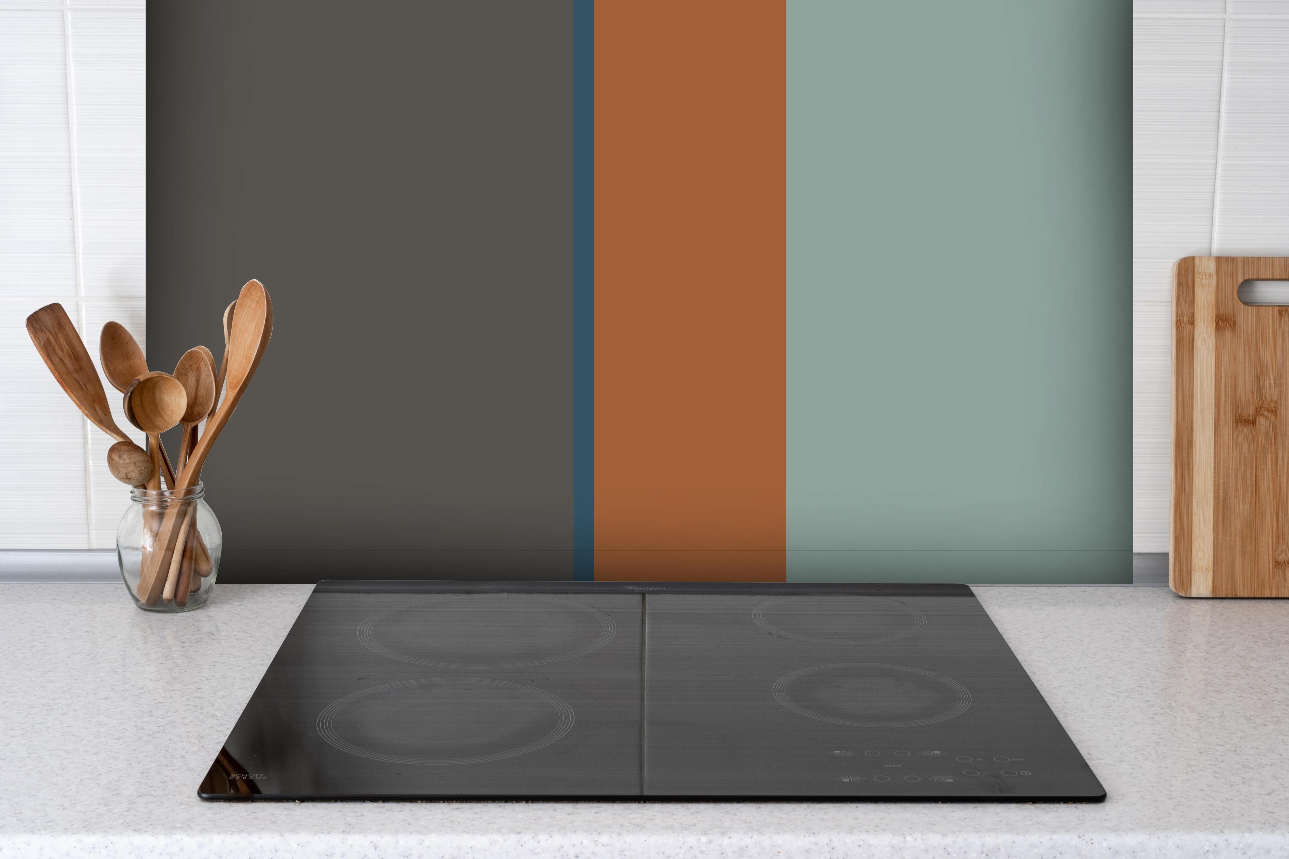 Spritzschutz - The Retros - Vertikal - Jon hinter einem Cerankochfeld zwischen Holz-Kochutensilien