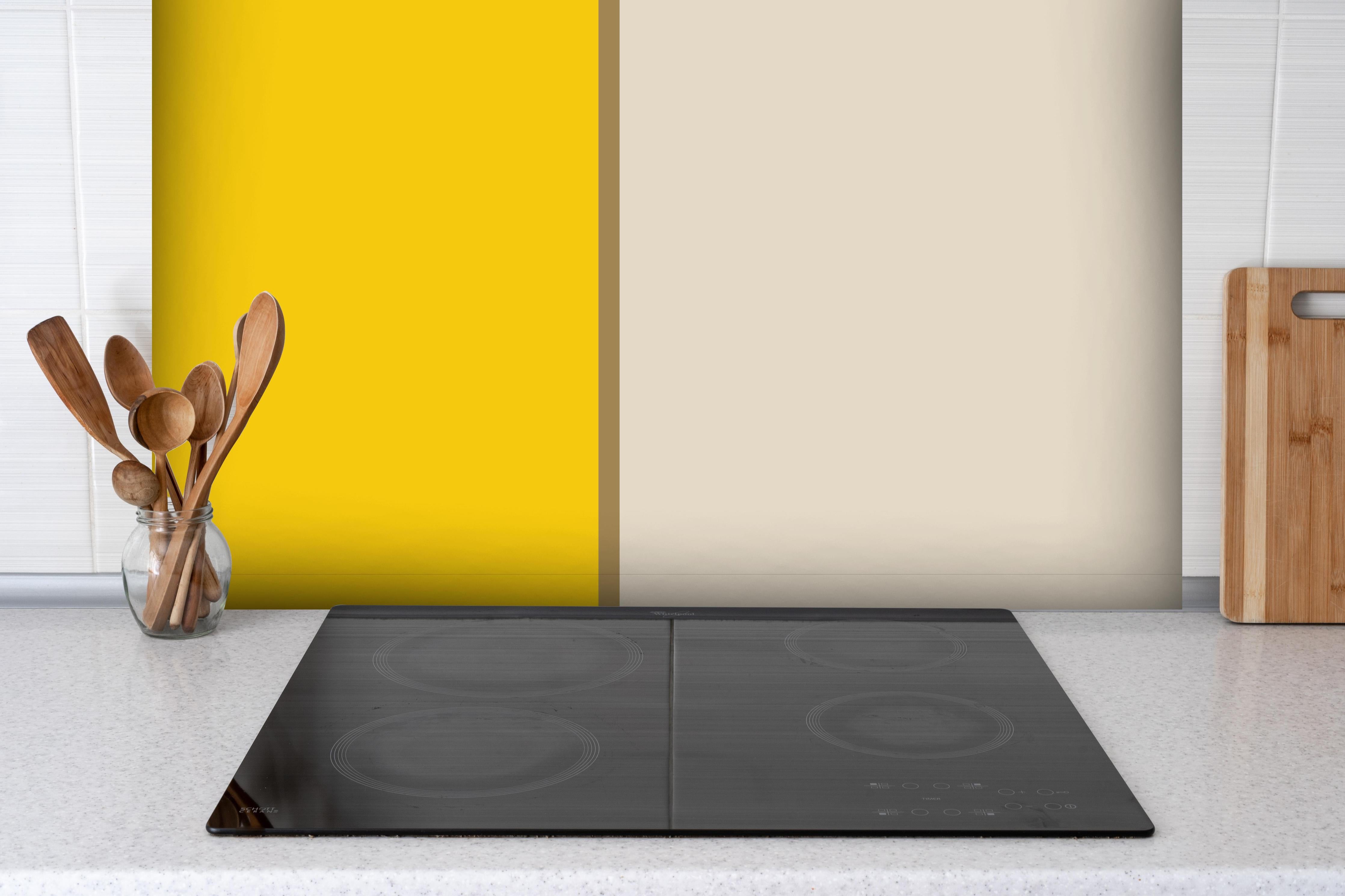 Spritzschutz - The Yellows - Easy Vertical - Saffron hinter einem Cerankochfeld zwischen Holz-Kochutensilien