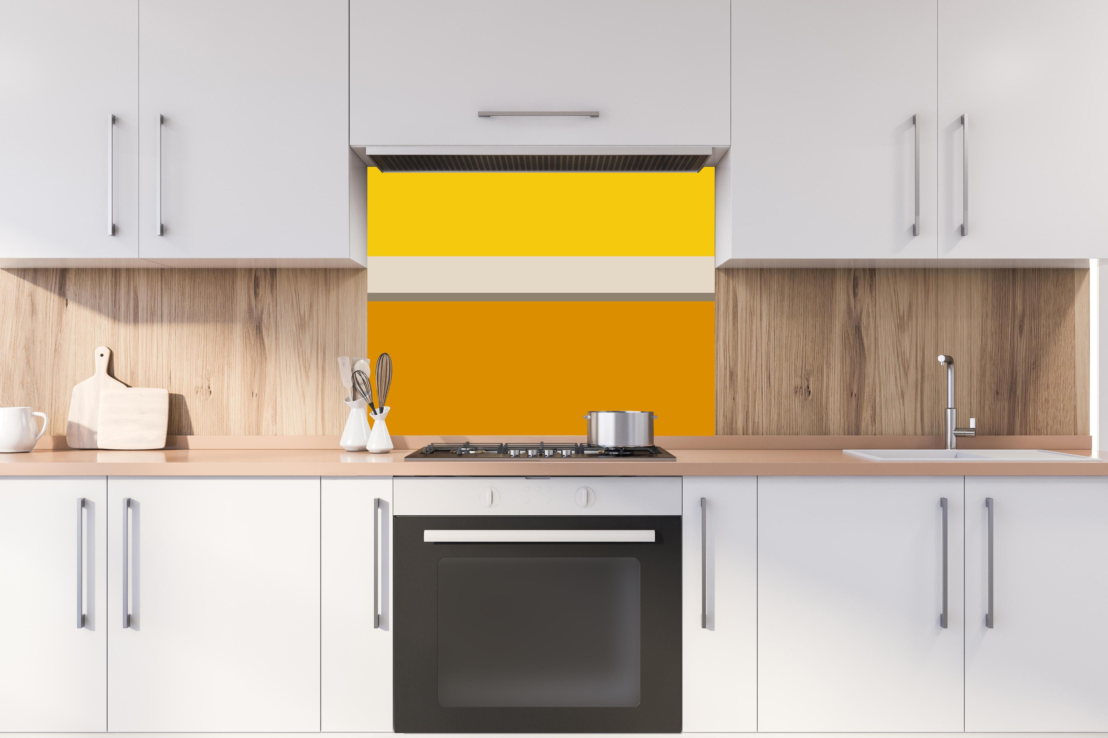 Spritzschutz - The Yellows - Horizontal - Saffron hinter einem Cerankochfeld zwischen Holz-Kochutensilien