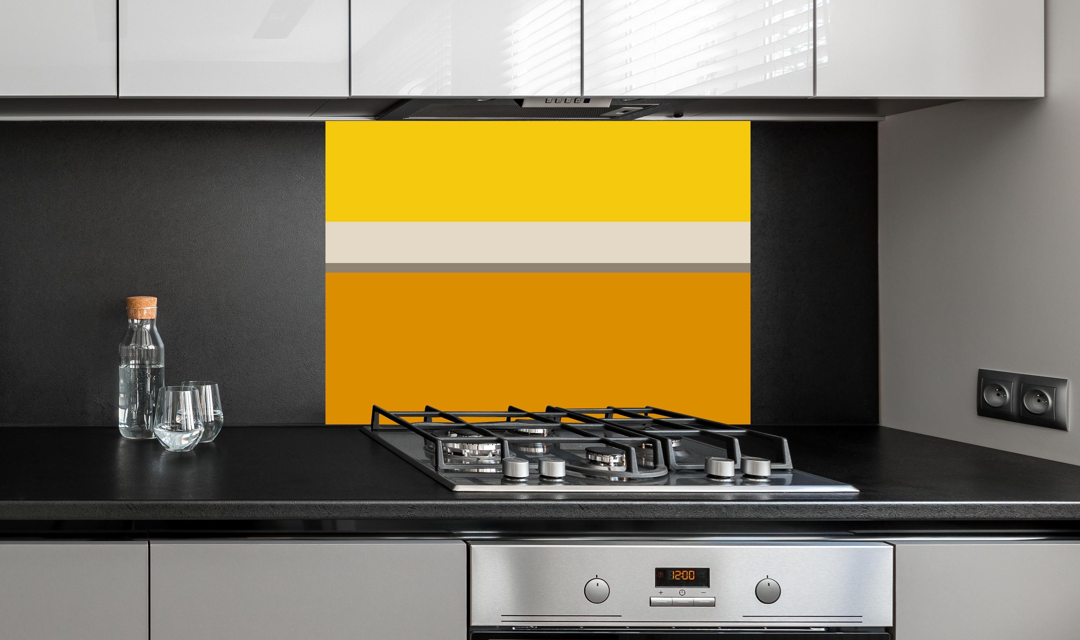 Spritzschutz - The Yellows - Horizontal - Saffron hinter einem Cerankochfeld zwischen Holz-Kochutensilien
