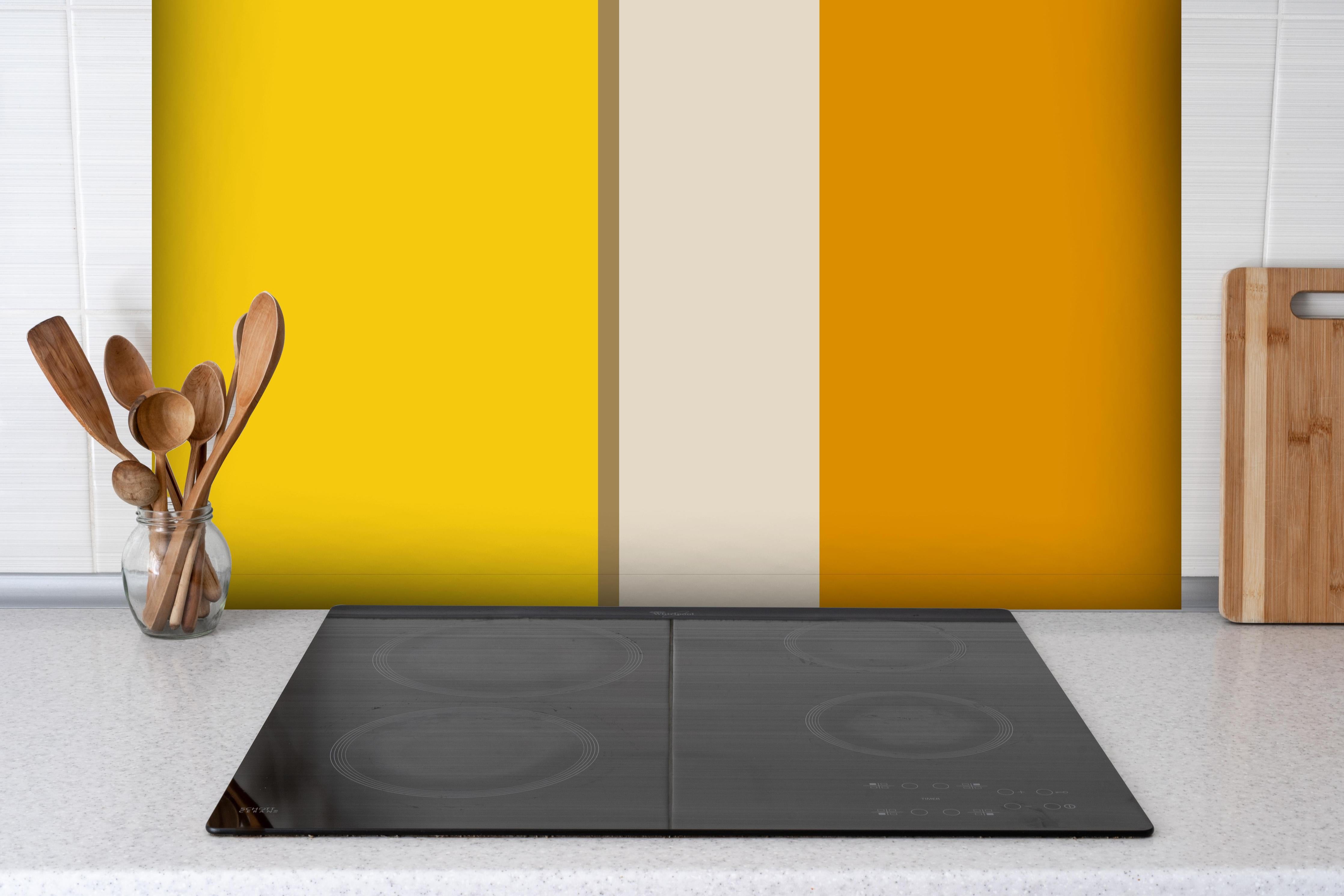 Spritzschutz - The Yellows - Vertical - Saffron hinter einem Cerankochfeld zwischen Holz-Kochutensilien