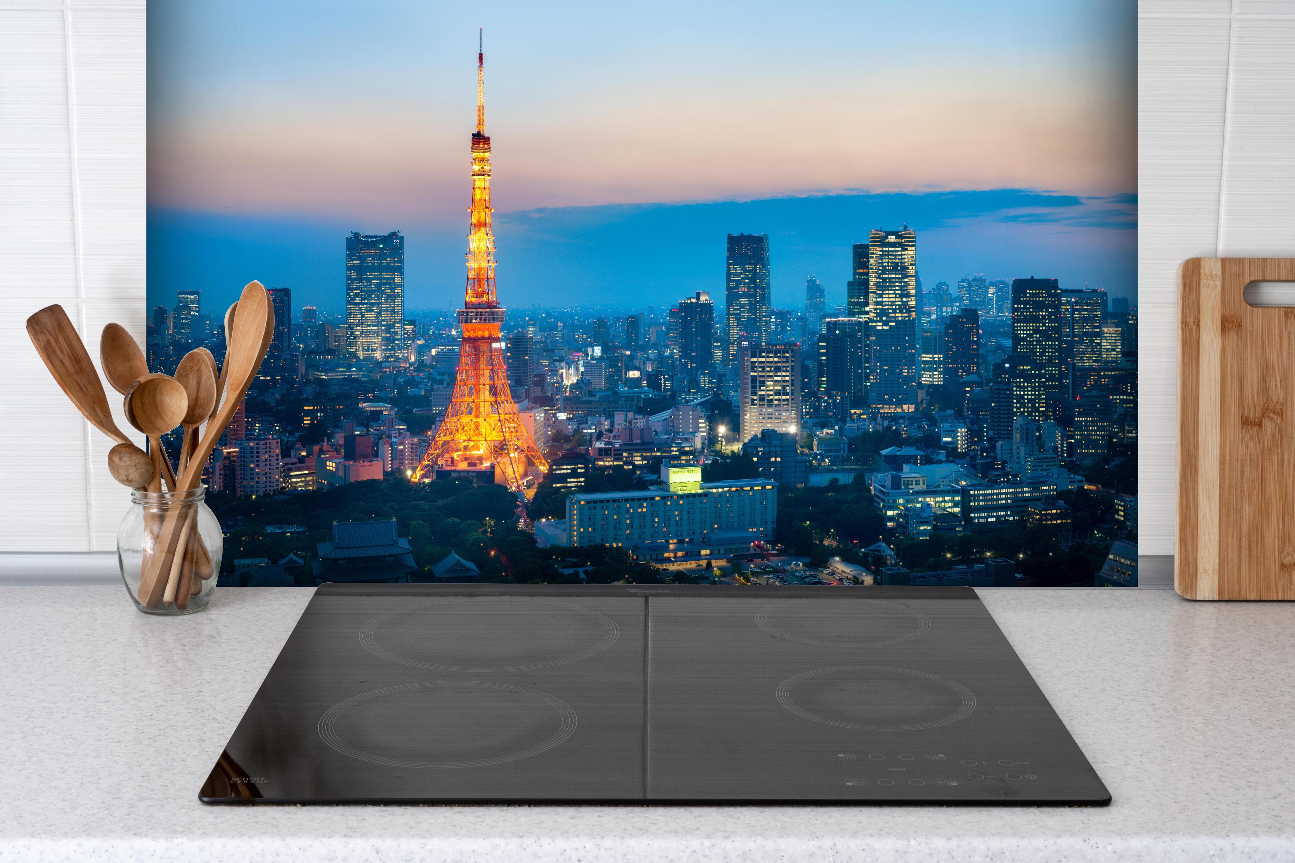 Spritzschutz - Tokyo Tower bei Nacht hinter einem Cerankochfeld zwischen Holz-Kochutensilien