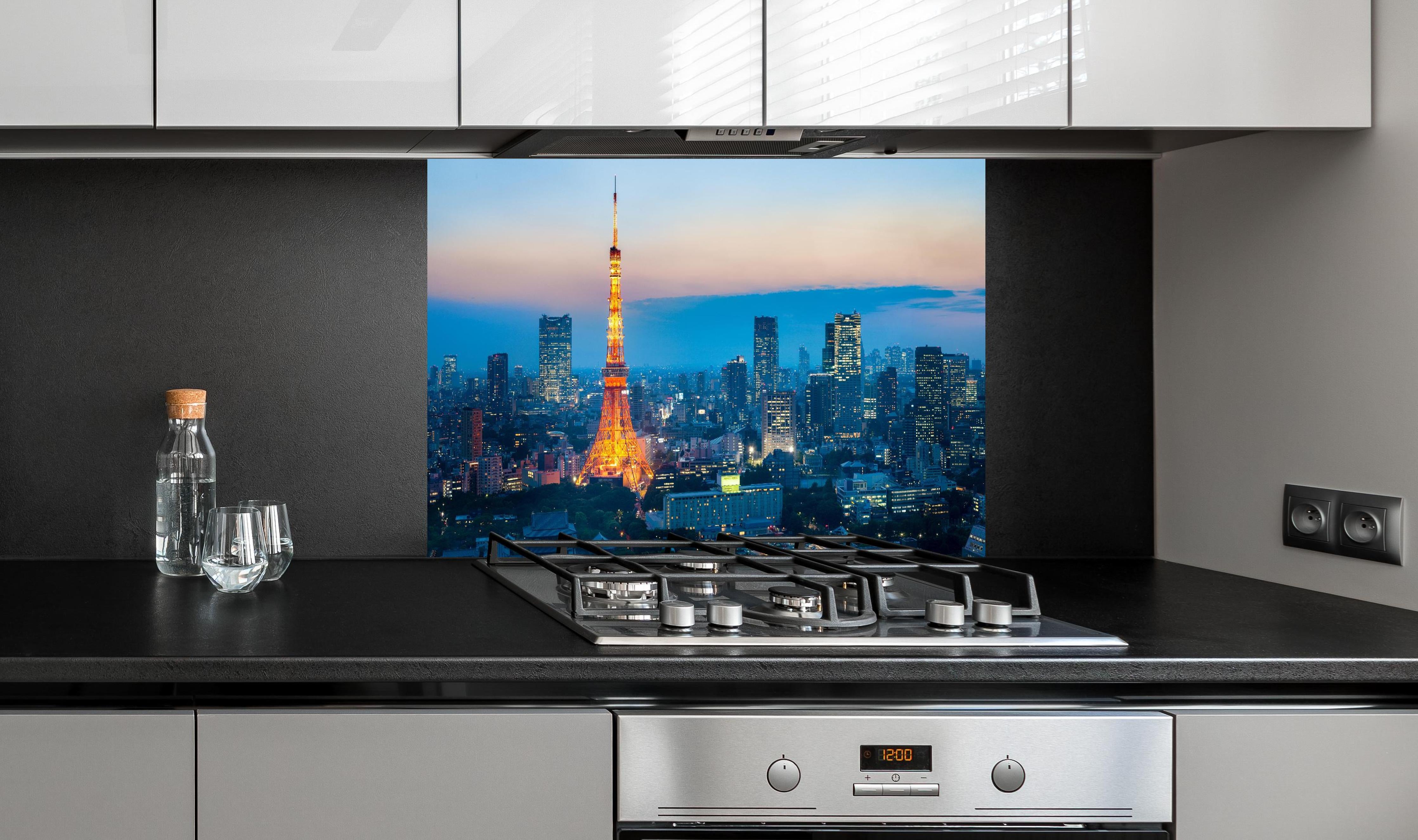 Spritzschutz - Tokyo Tower bei Nacht hinter einem Cerankochfeld zwischen Holz-Kochutensilien