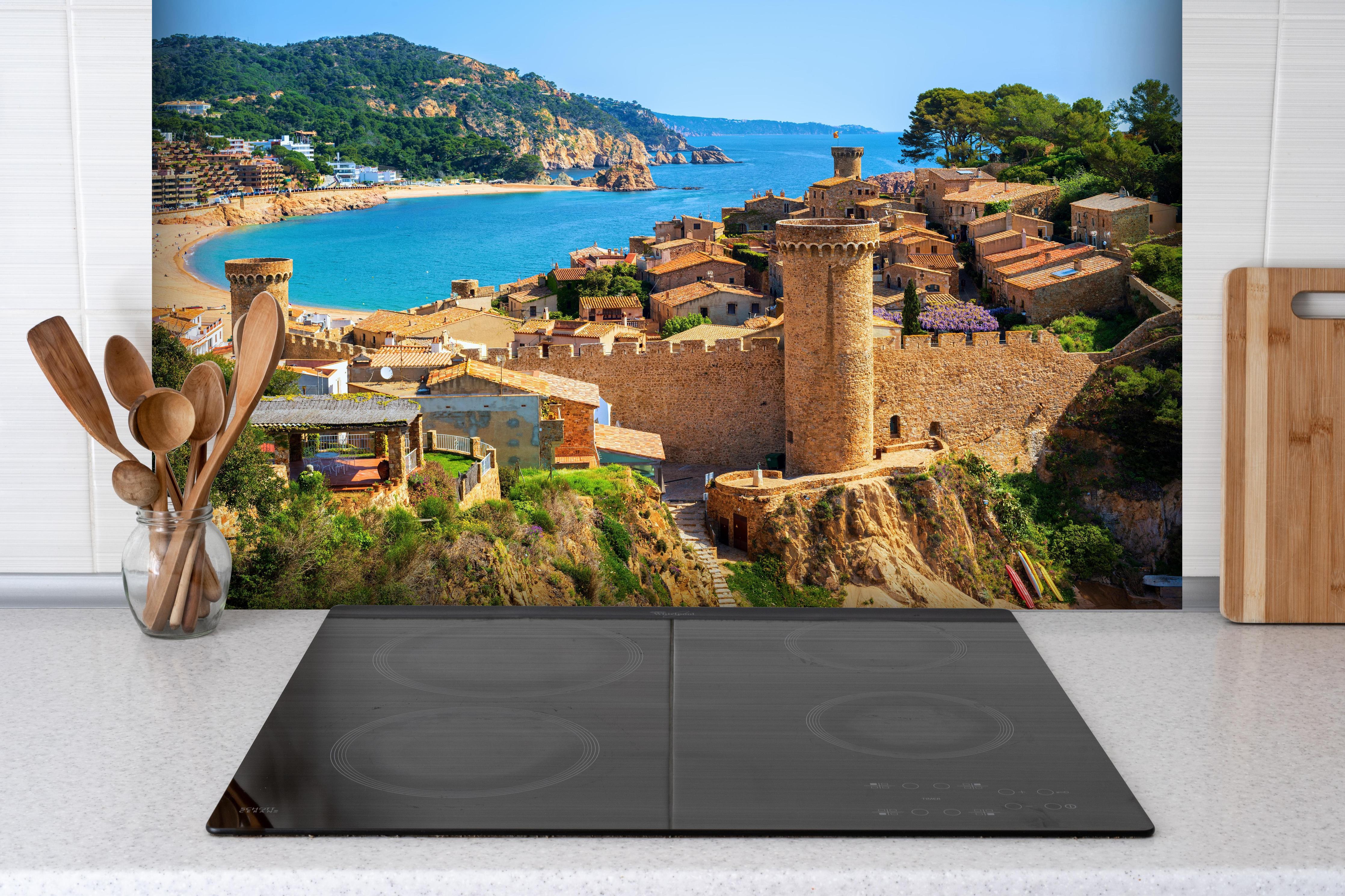 Spritzschutz - Tossa de Mar - Spanien hinter einem Cerankochfeld zwischen Holz-Kochutensilien