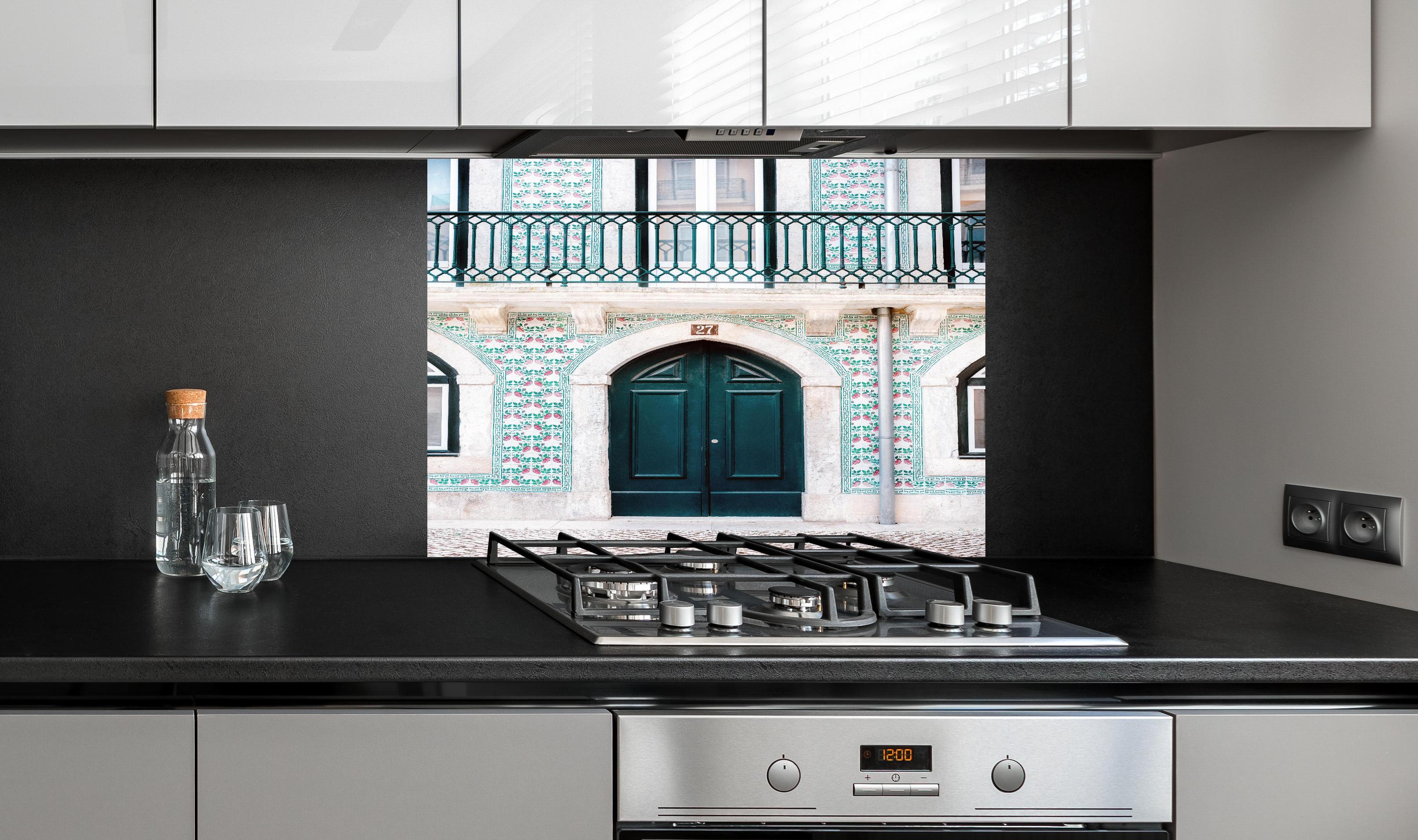 Spritzschutz - Traditionelle Tür Lissabons in Grün hinter einem Cerankochfeld zwischen Holz-Kochutensilien