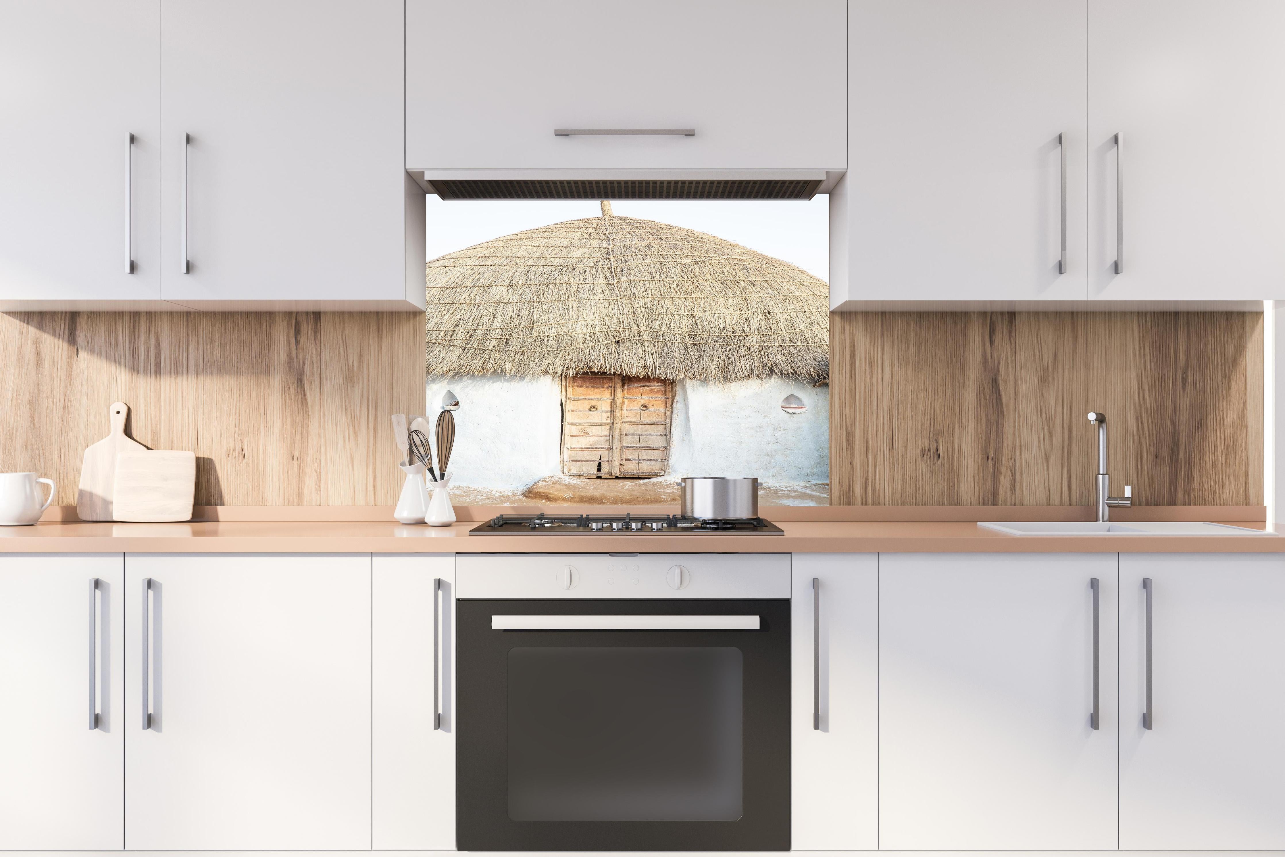 Spritzschutz - Traditionelle Wüstenhütte mit Strohdach hinter einem Cerankochfeld zwischen Holz-Kochutensilien