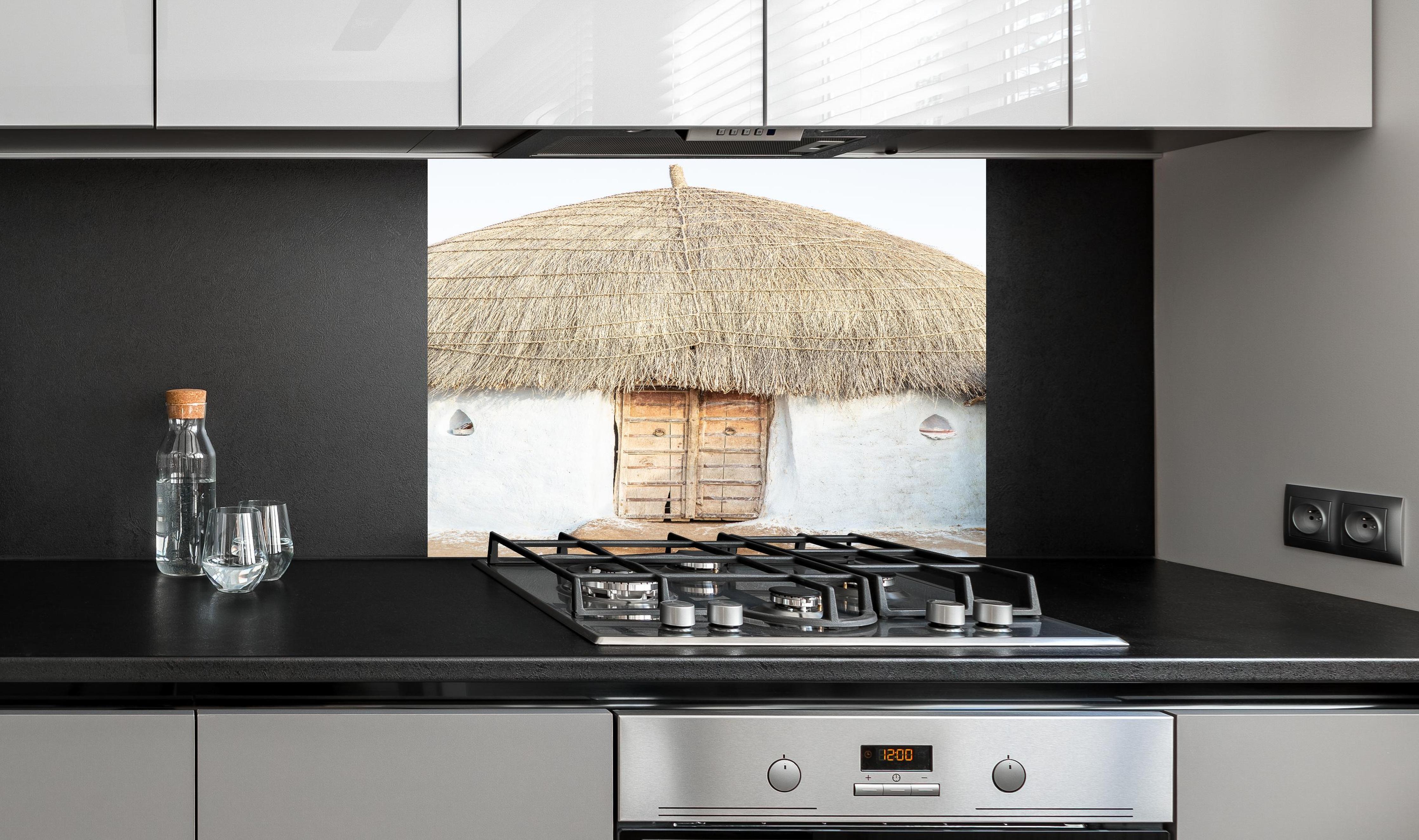 Spritzschutz - Traditionelle Wüstenhütte mit Strohdach hinter einem Cerankochfeld zwischen Holz-Kochutensilien