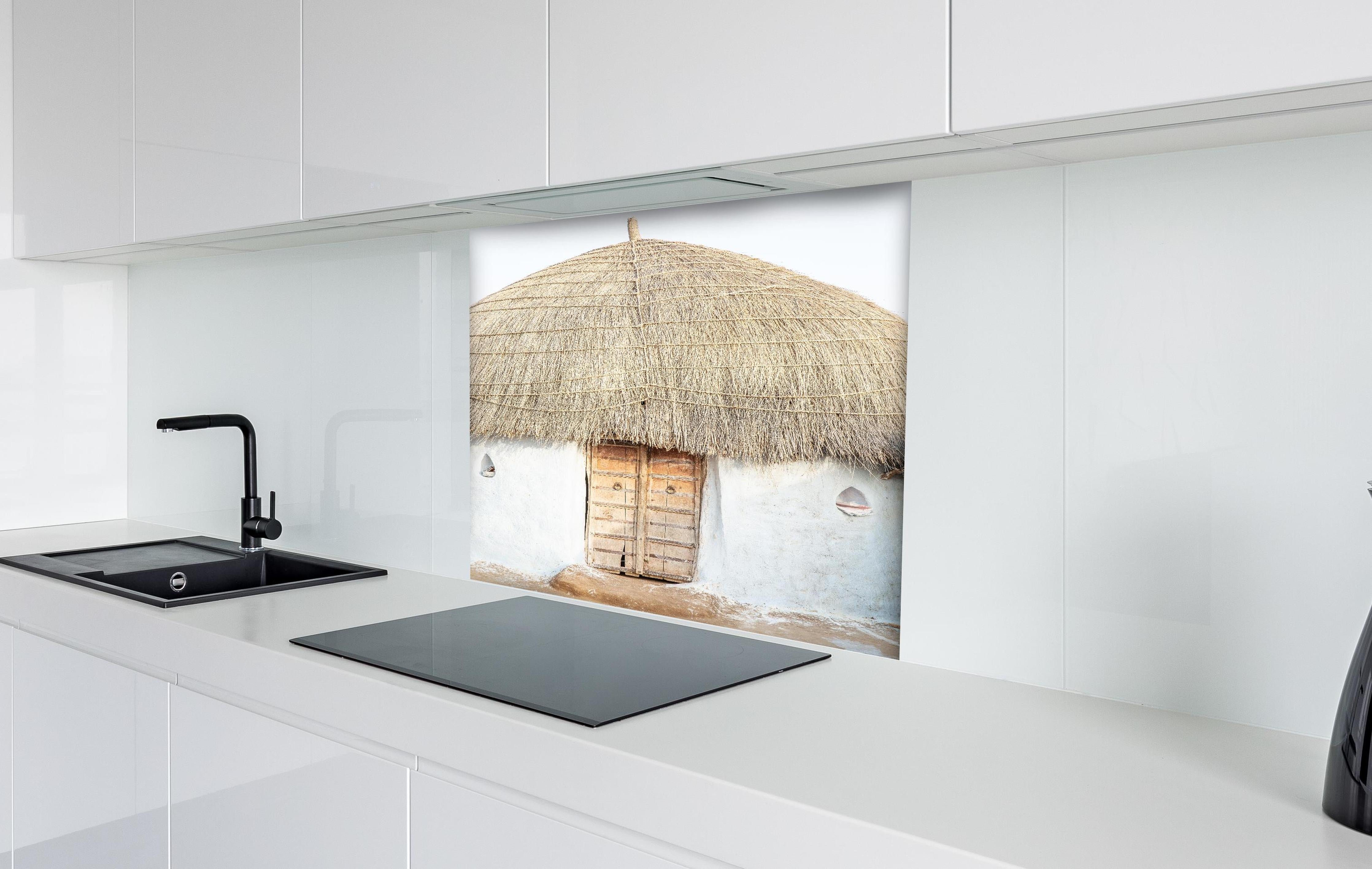 Spritzschutz - Traditionelle Wüstenhütte mit Strohdach hinter einem Cerankochfeld zwischen Holz-Kochutensilien