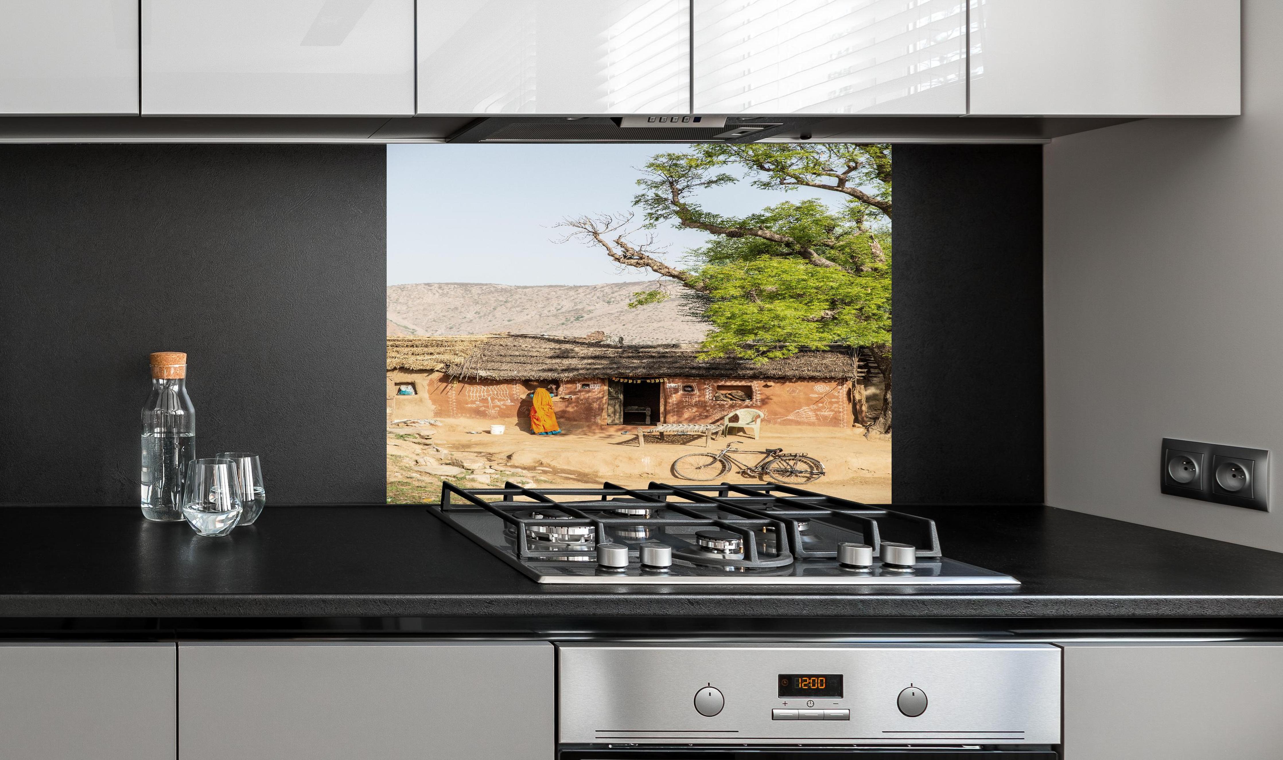 Spritzschutz - Traditionelles Dorf, Baum und Fahrrad hinter einem Cerankochfeld zwischen Holz-Kochutensilien