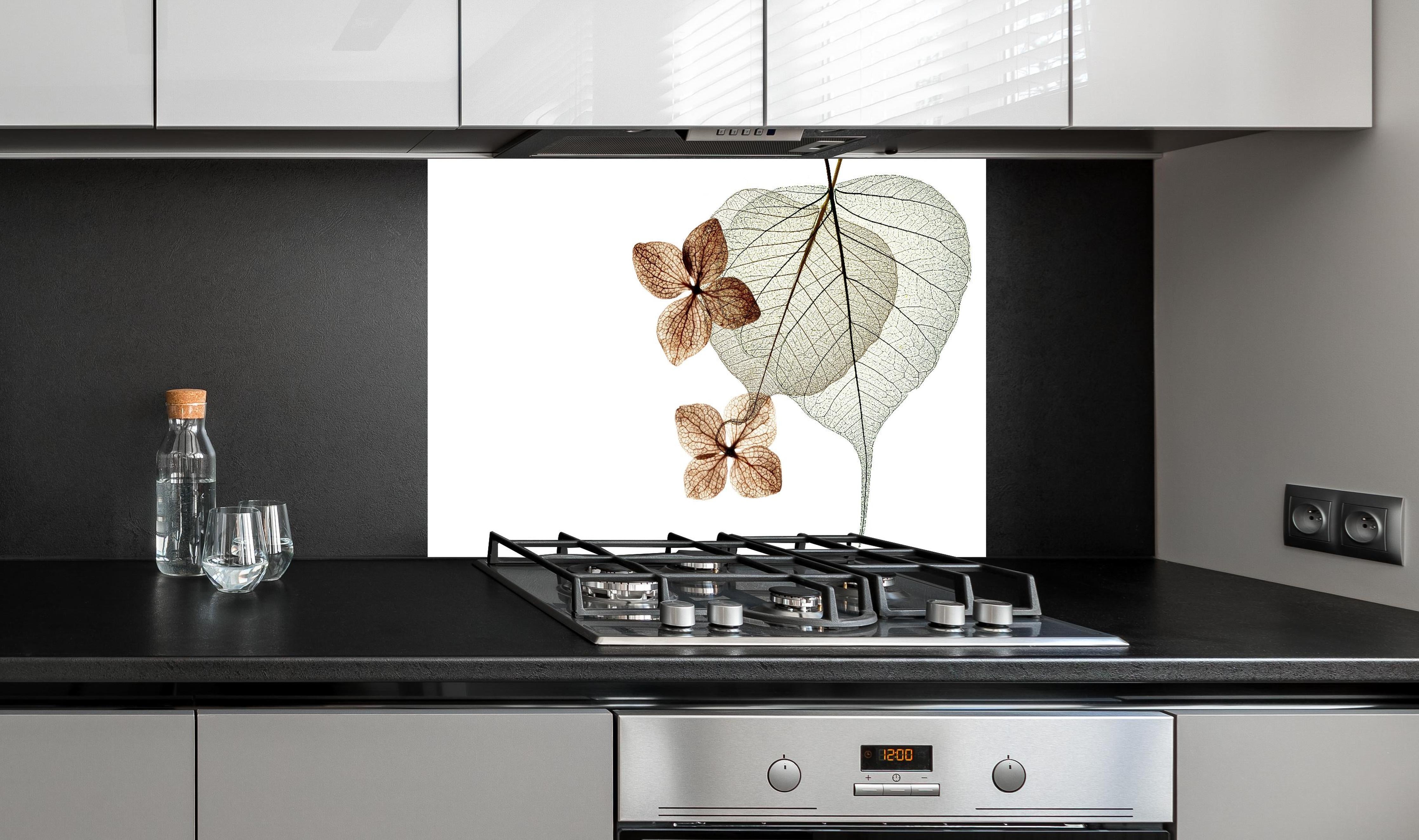 Spritzschutz - Transparente Blattstrukturen in Weiß-Grau hinter einem Cerankochfeld zwischen Holz-Kochutensilien