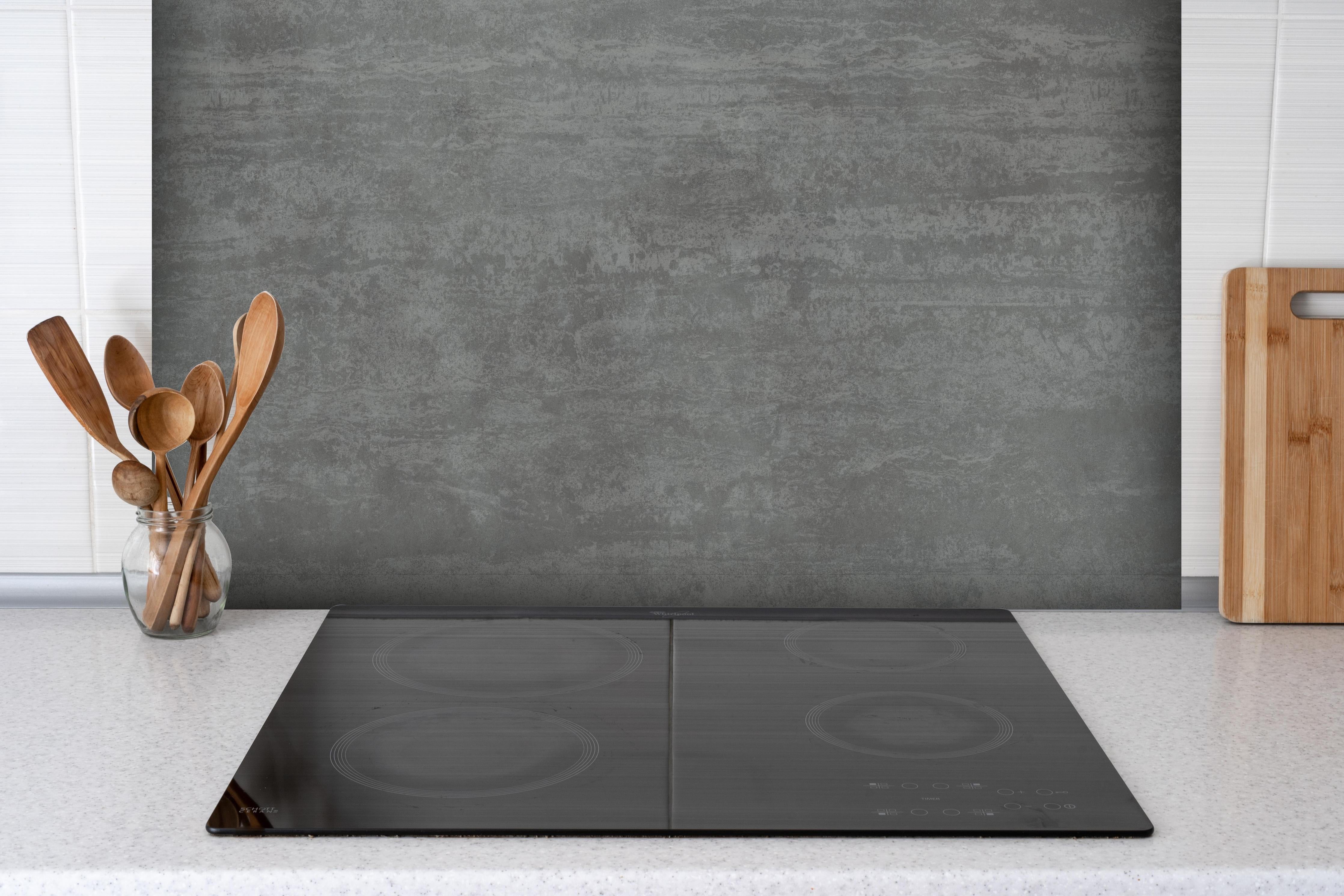 Spritzschutz - Travertino Marmor Textur hinter einem Cerankochfeld zwischen Holz-Kochutensilien