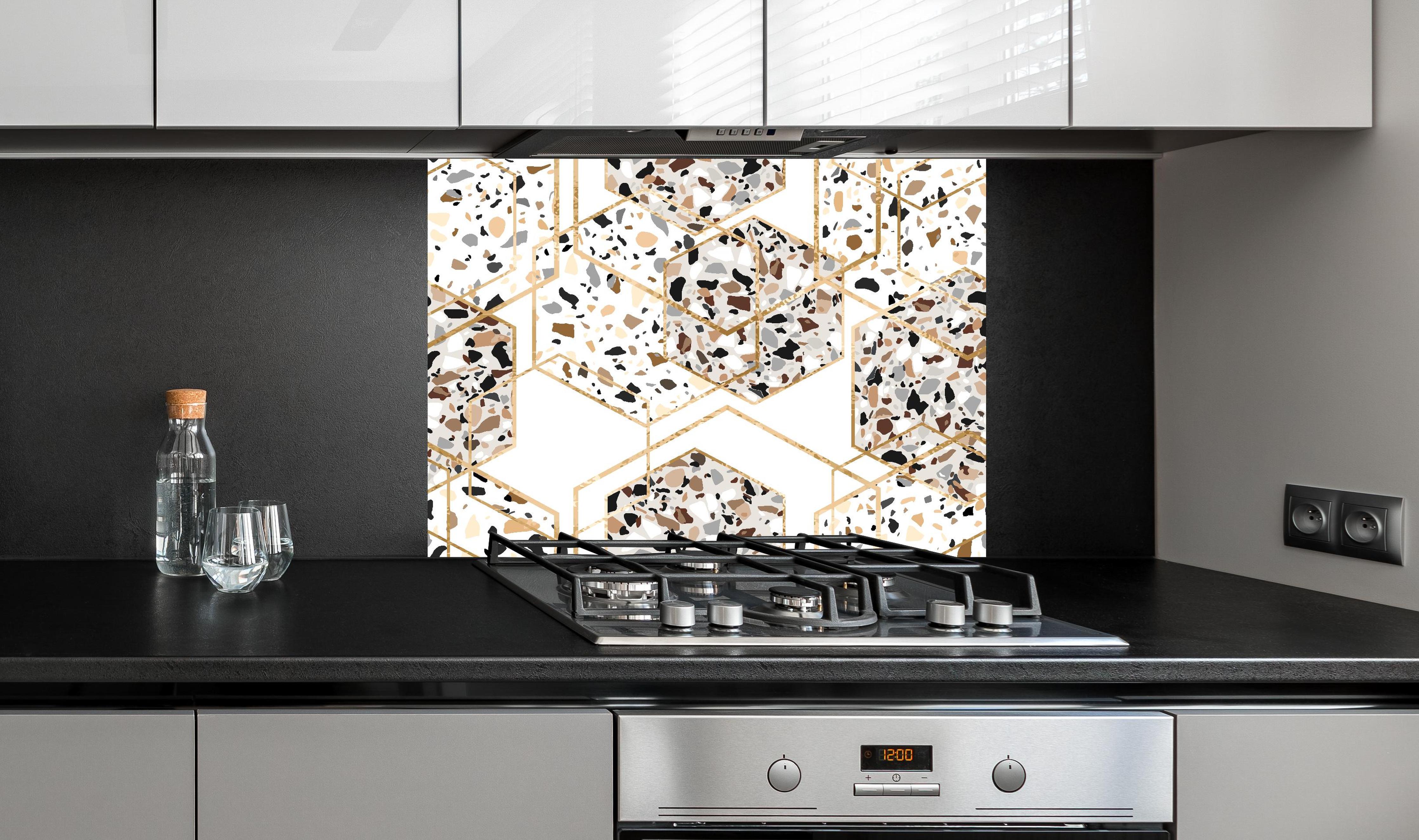 Spritzschutz - Trendiges Terrazzo-Muster mit Goldakzenten hinter einem Cerankochfeld zwischen Holz-Kochutensilien
