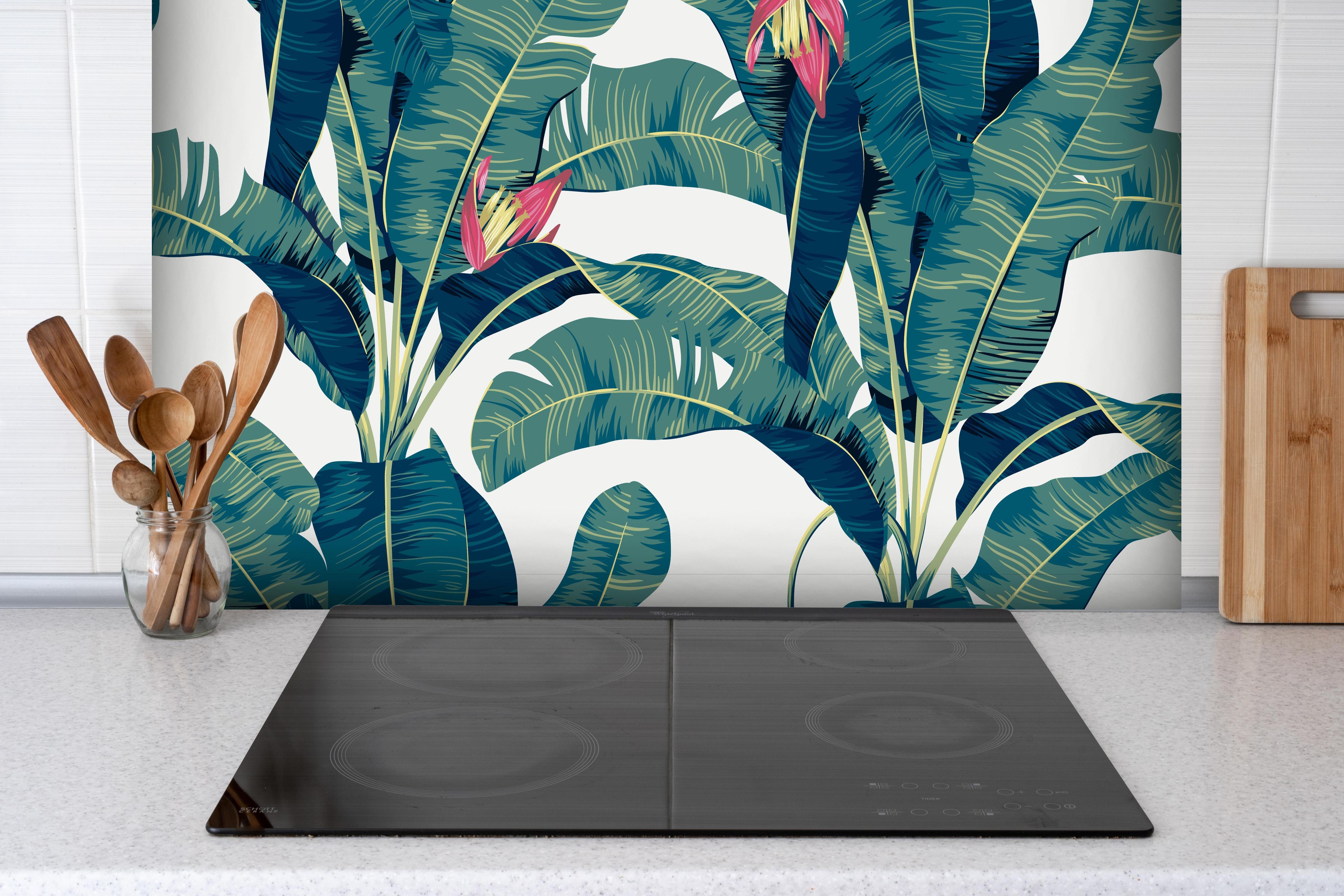 Spritzschutz - Tropisch Grün hinter einem Cerankochfeld zwischen Holz-Kochutensilien