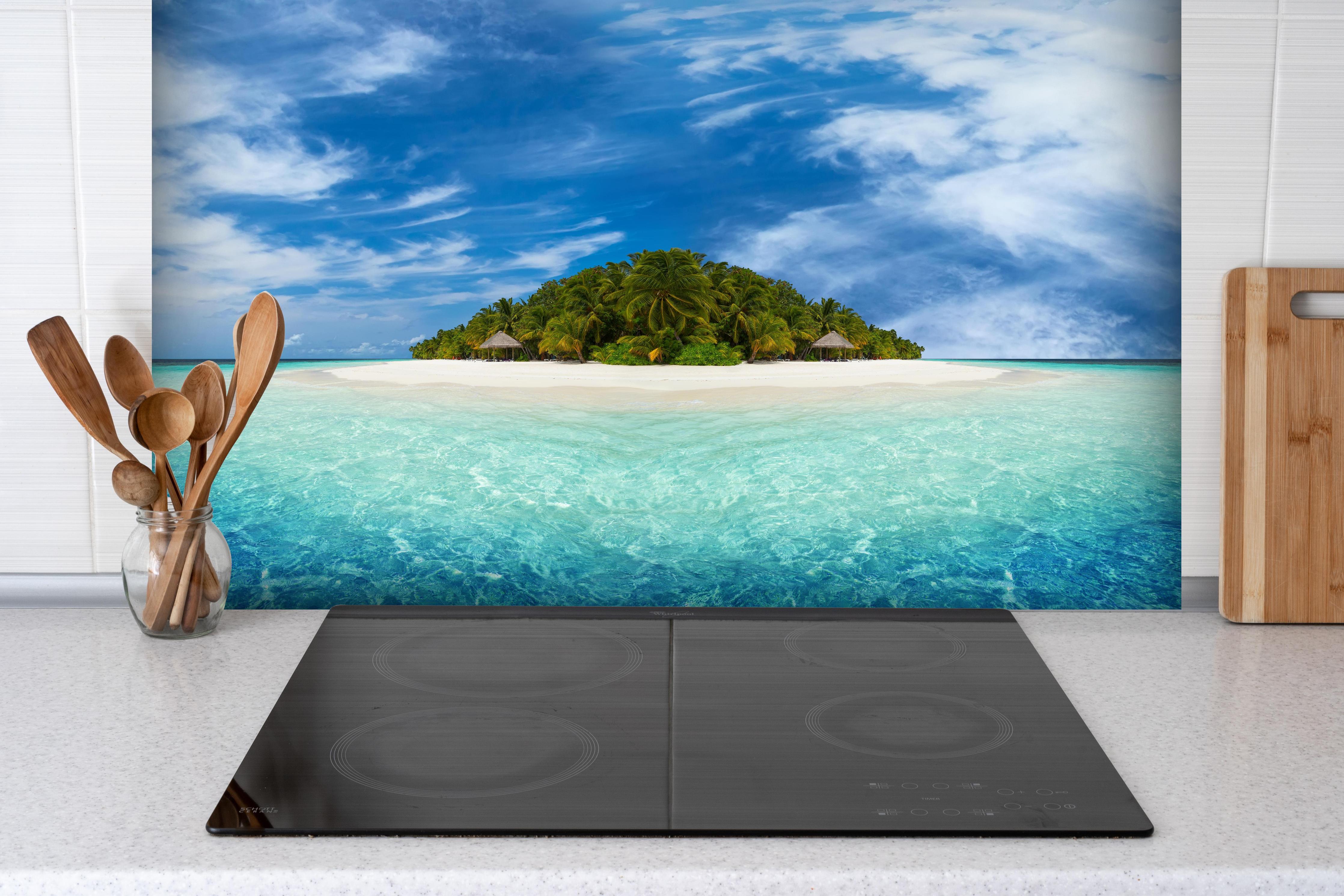 Spritzschutz - Tropische Insel mit Kokospalmen hinter einem Cerankochfeld zwischen Holz-Kochutensilien