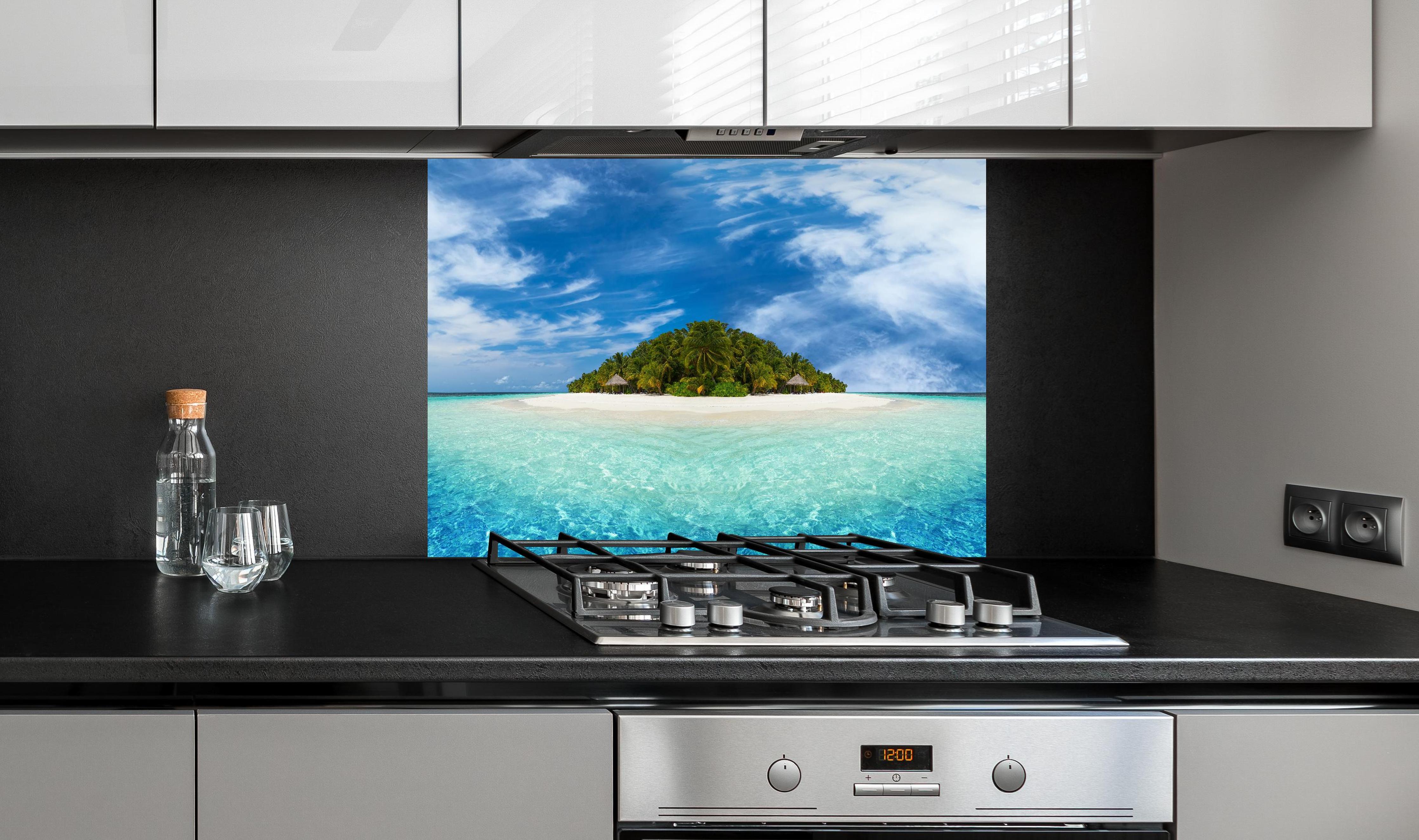 Spritzschutz - Tropische Insel mit Kokospalmen hinter einem Cerankochfeld zwischen Holz-Kochutensilien