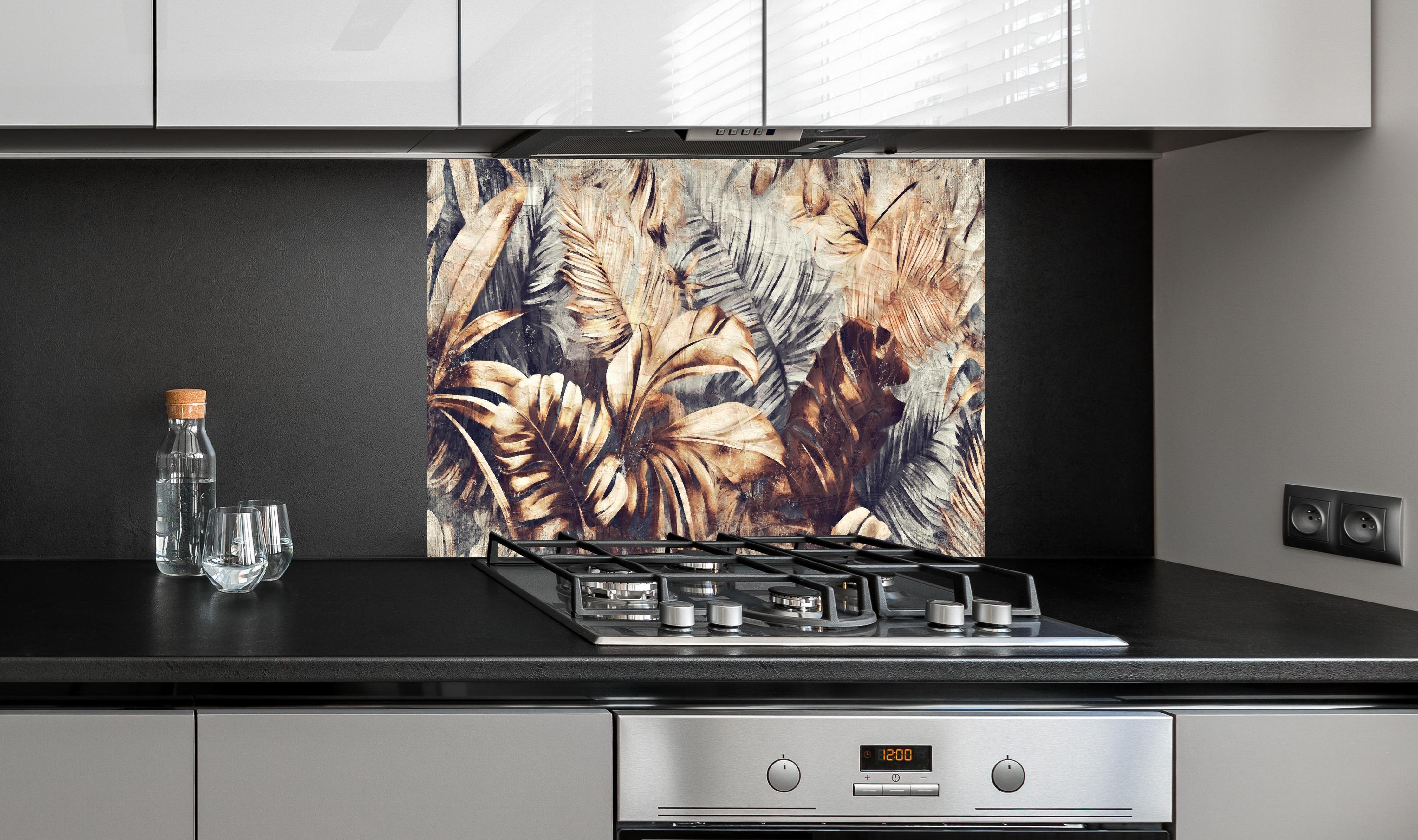 Spritzschutz - Tropische Palmenblätter in Gelb-Braun hinter einem Cerankochfeld zwischen Holz-Kochutensilien