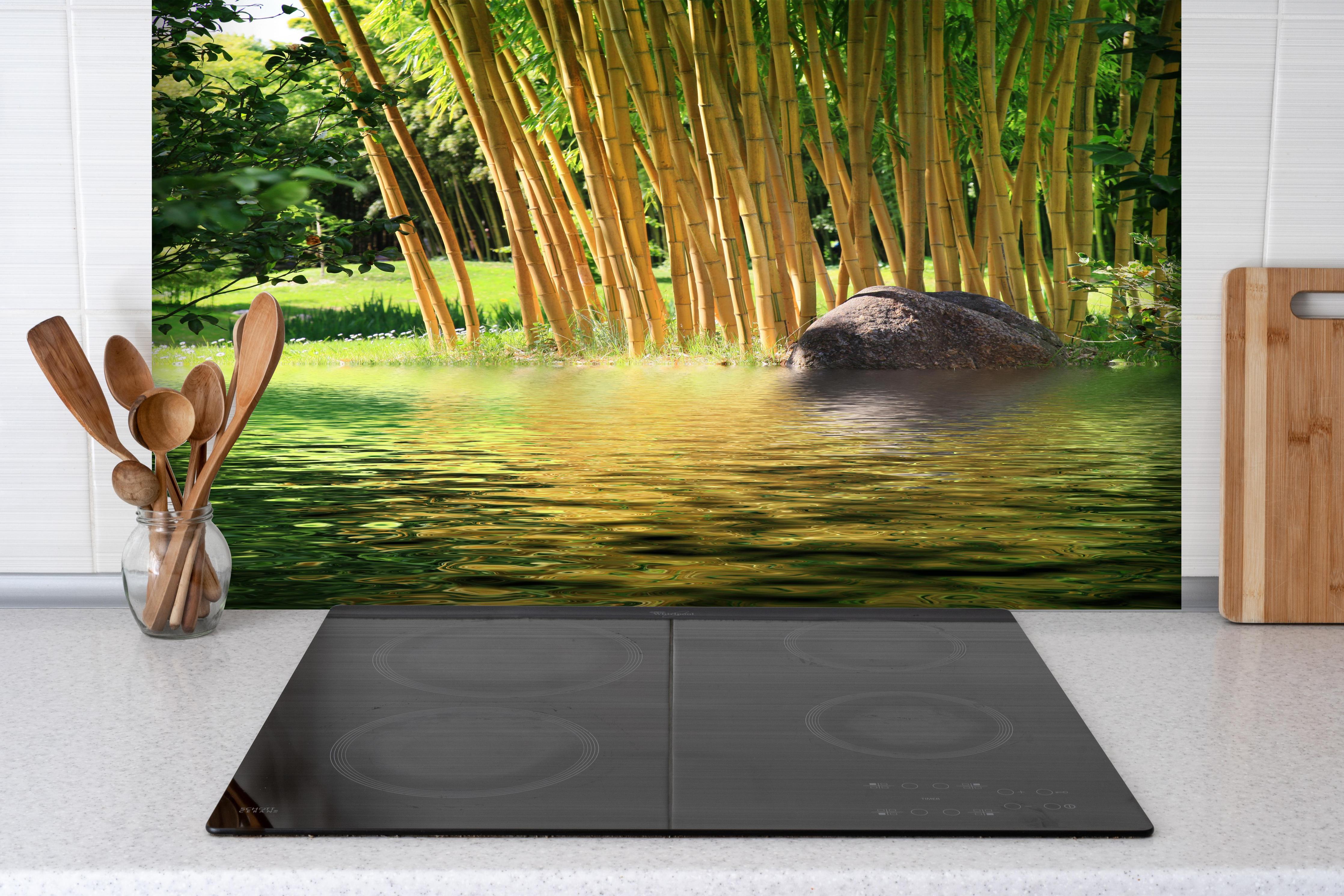 Spritzschutz - Tropischer Bambuswald mit See in Zentralasien hinter einem Cerankochfeld zwischen Holz-Kochutensilien