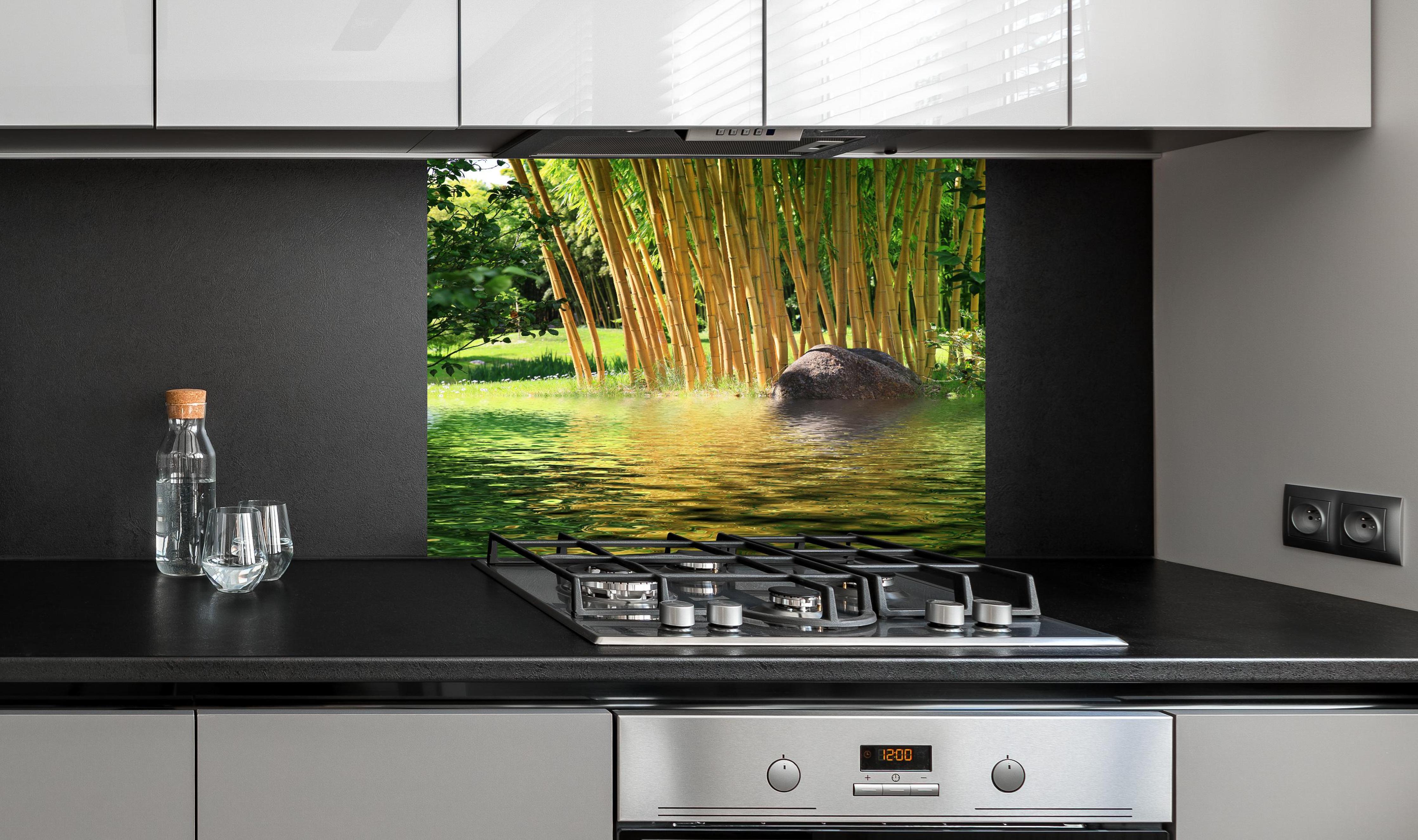 Spritzschutz - Tropischer Bambuswald mit See in Zentralasien hinter einem Cerankochfeld zwischen Holz-Kochutensilien