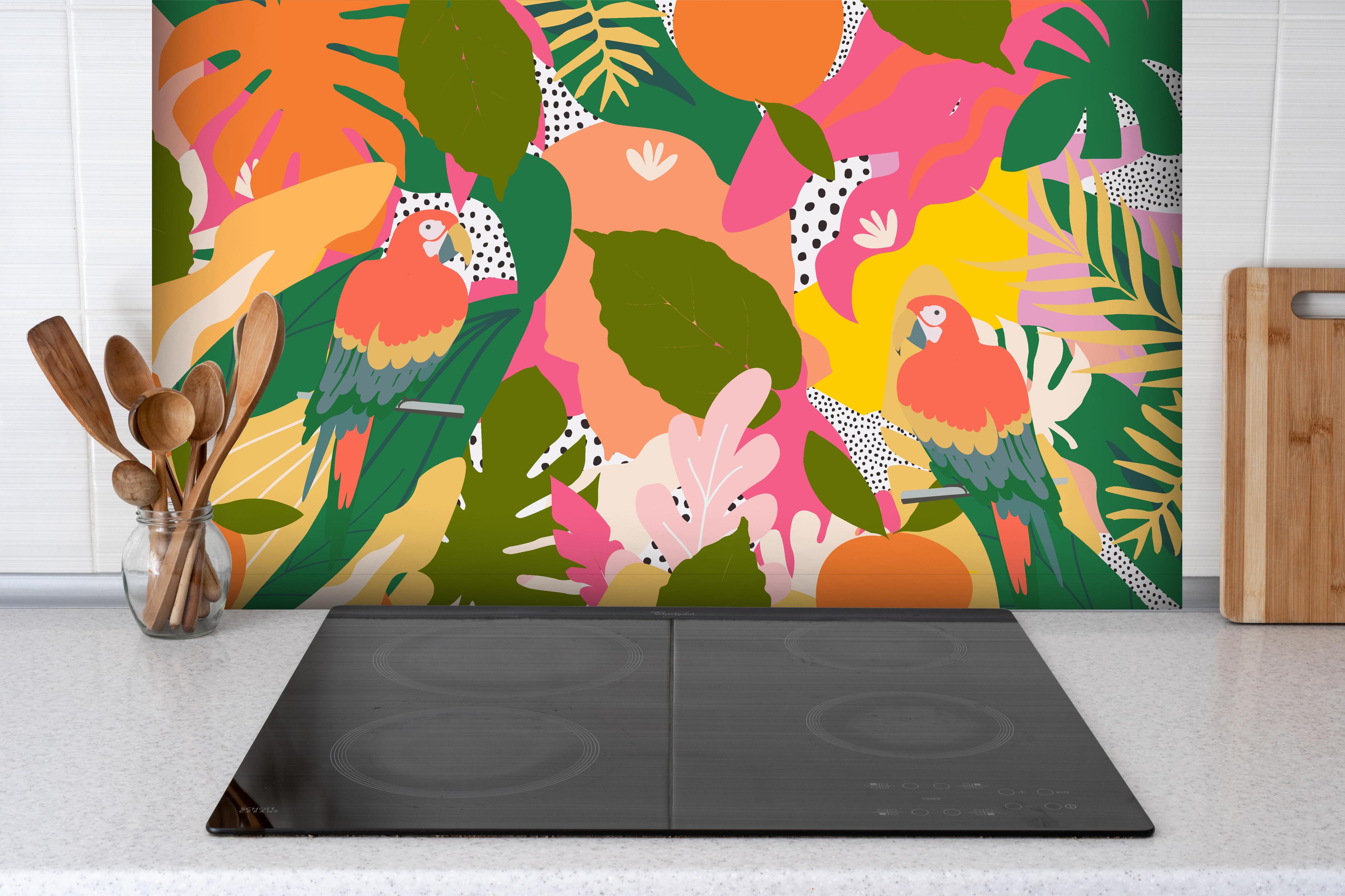 Spritzschutz - Tropischer Dschungel mit bunten Papageien hinter einem Cerankochfeld zwischen Holz-Kochutensilien