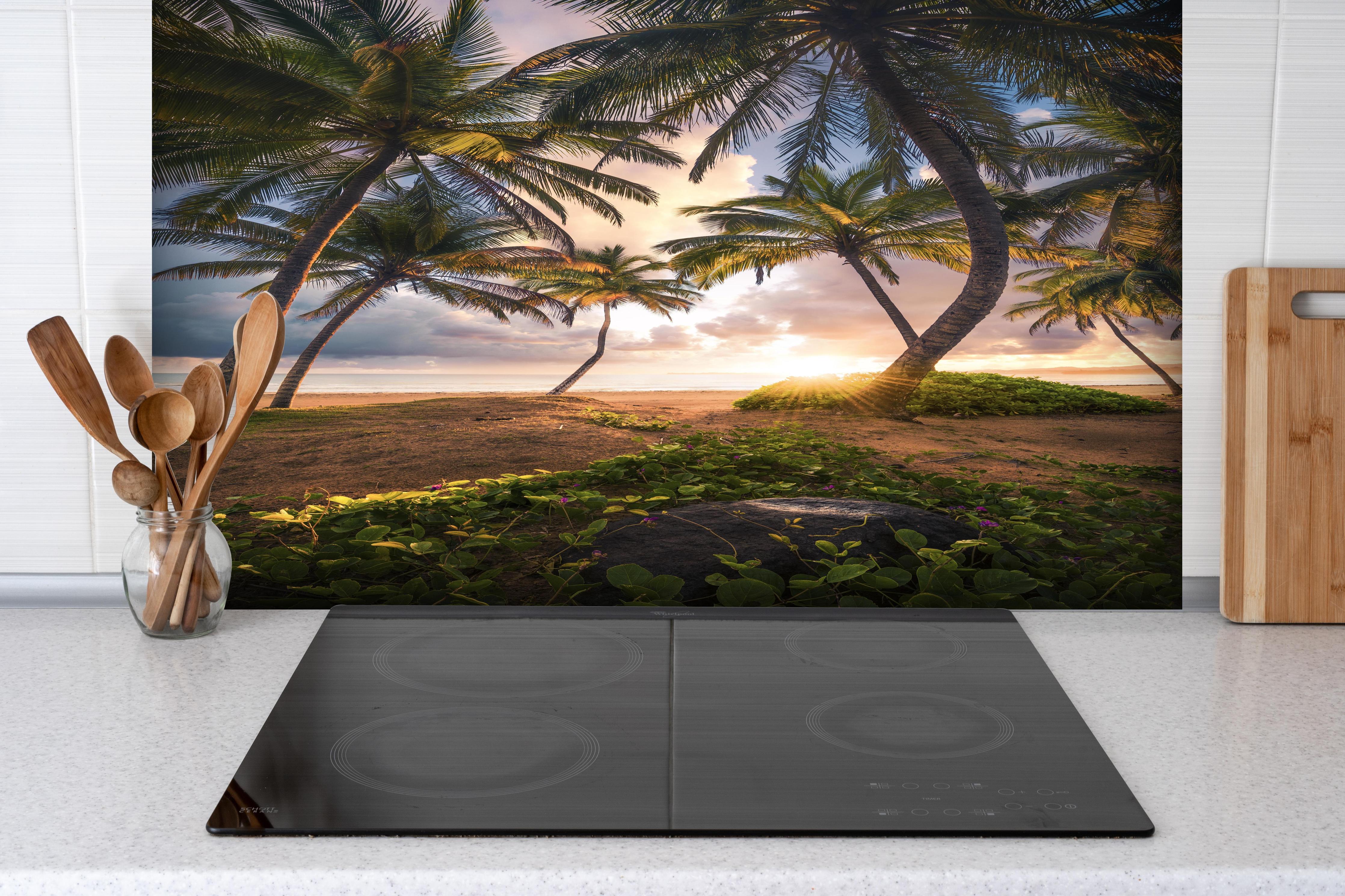 Spritzschutz - Tropischer Strand Sonnenaufgang mit Palmen hinter einem Cerankochfeld zwischen Holz-Kochutensilien