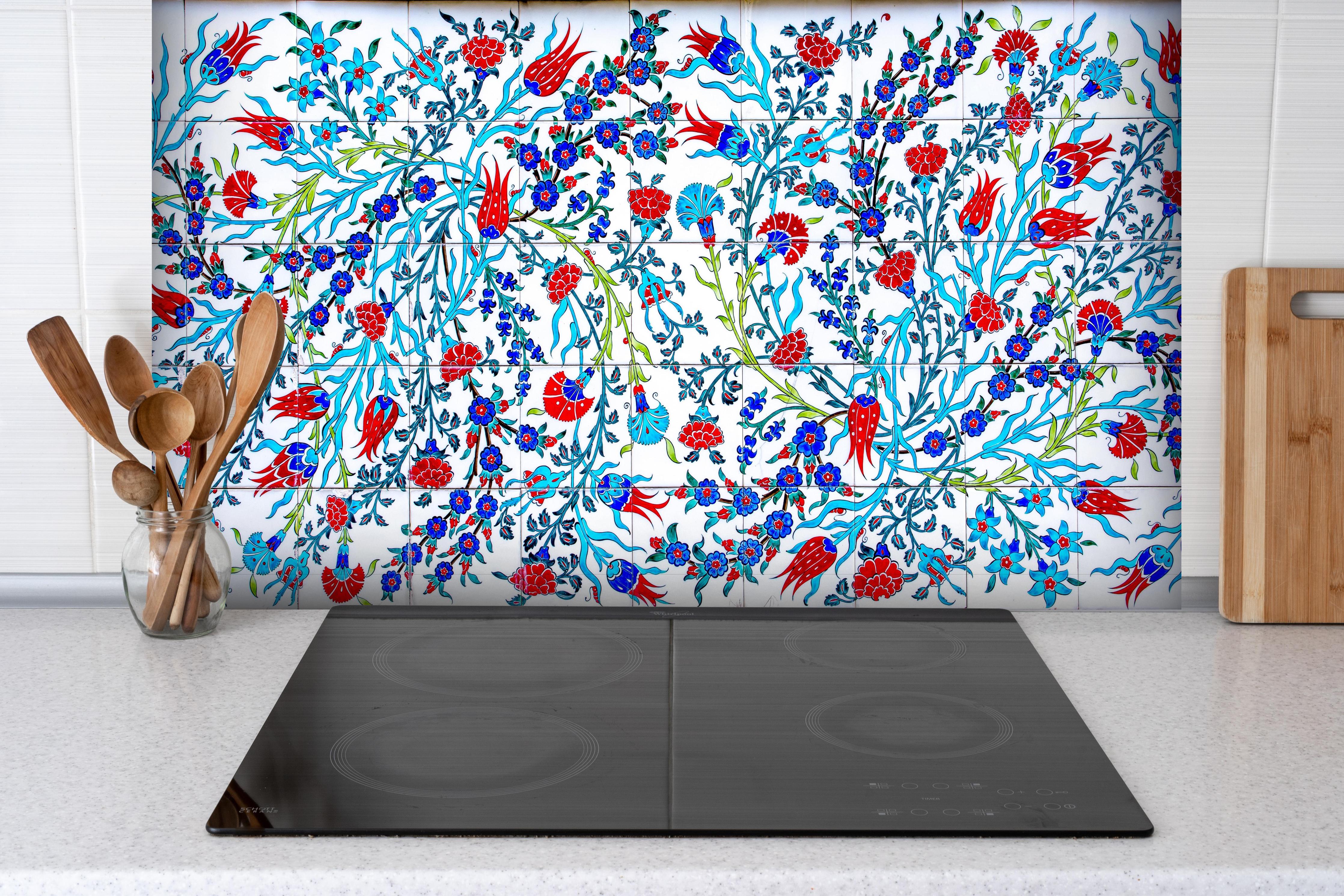 Spritzschutz - Türkische Wandfliese mit floralem Muster hinter einem Cerankochfeld zwischen Holz-Kochutensilien