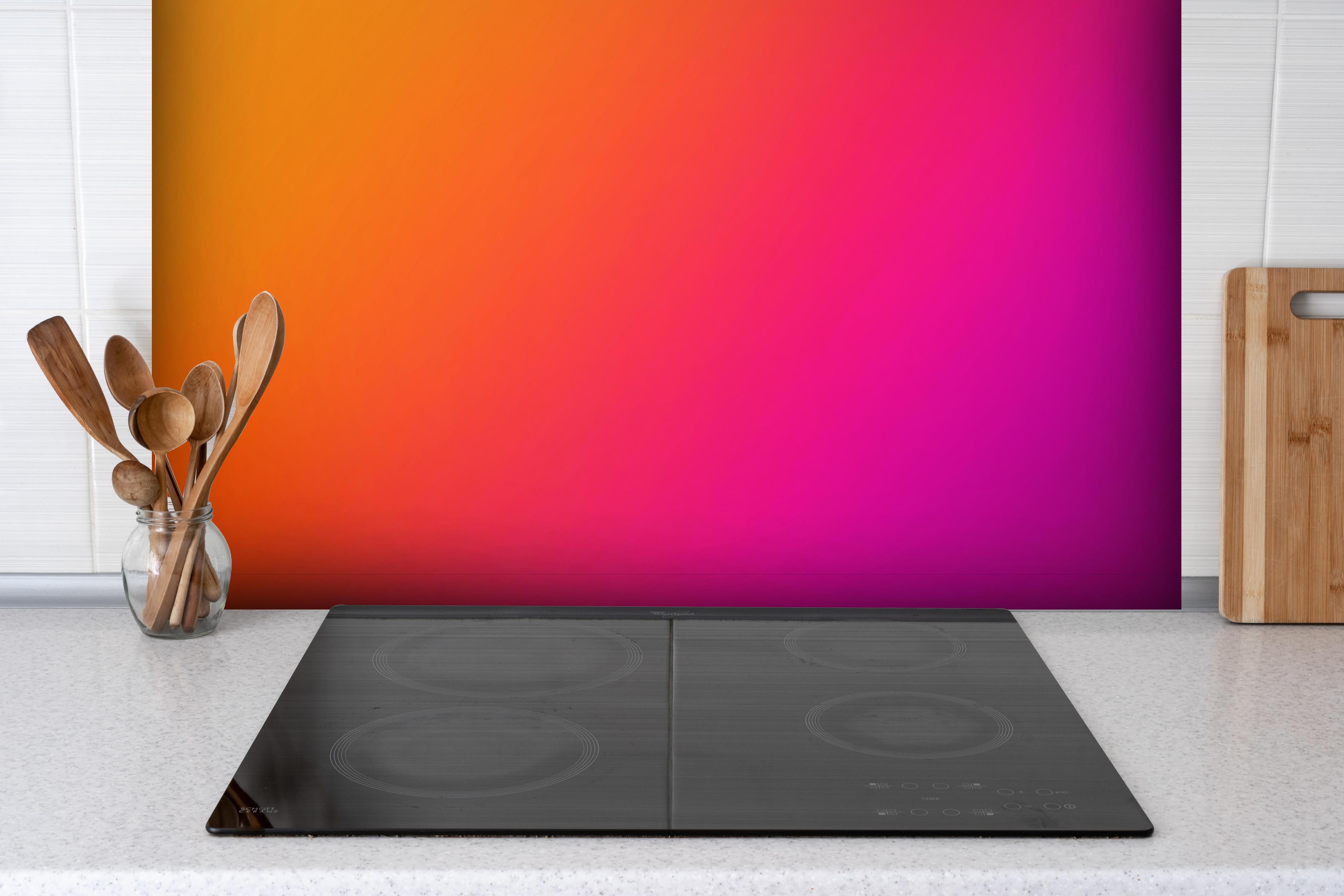 Spritzschutz - Übergang von orange zu lila hinter einem Cerankochfeld zwischen Holz-Kochutensilien