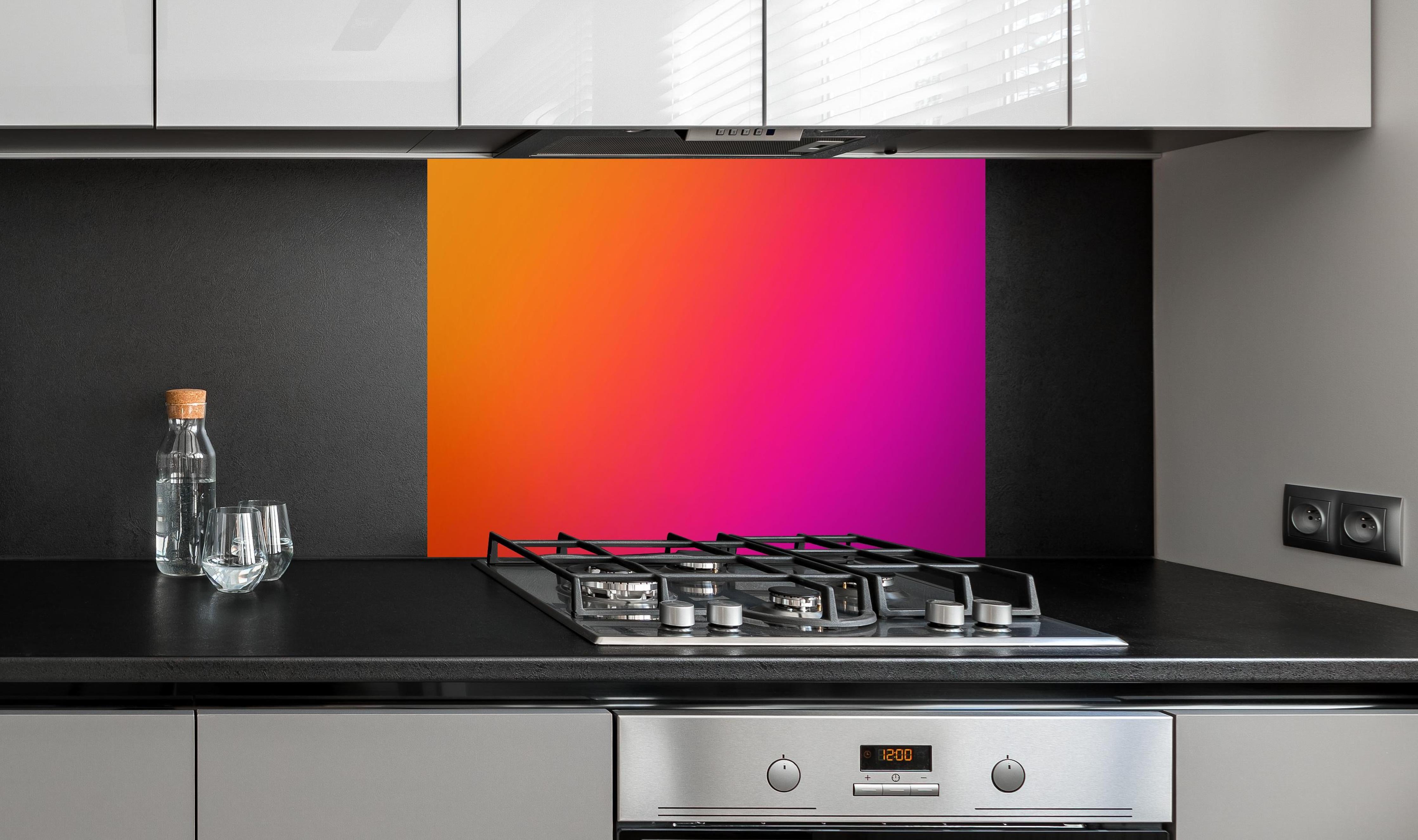 Spritzschutz - Übergang von orange zu lila hinter einem Cerankochfeld zwischen Holz-Kochutensilien