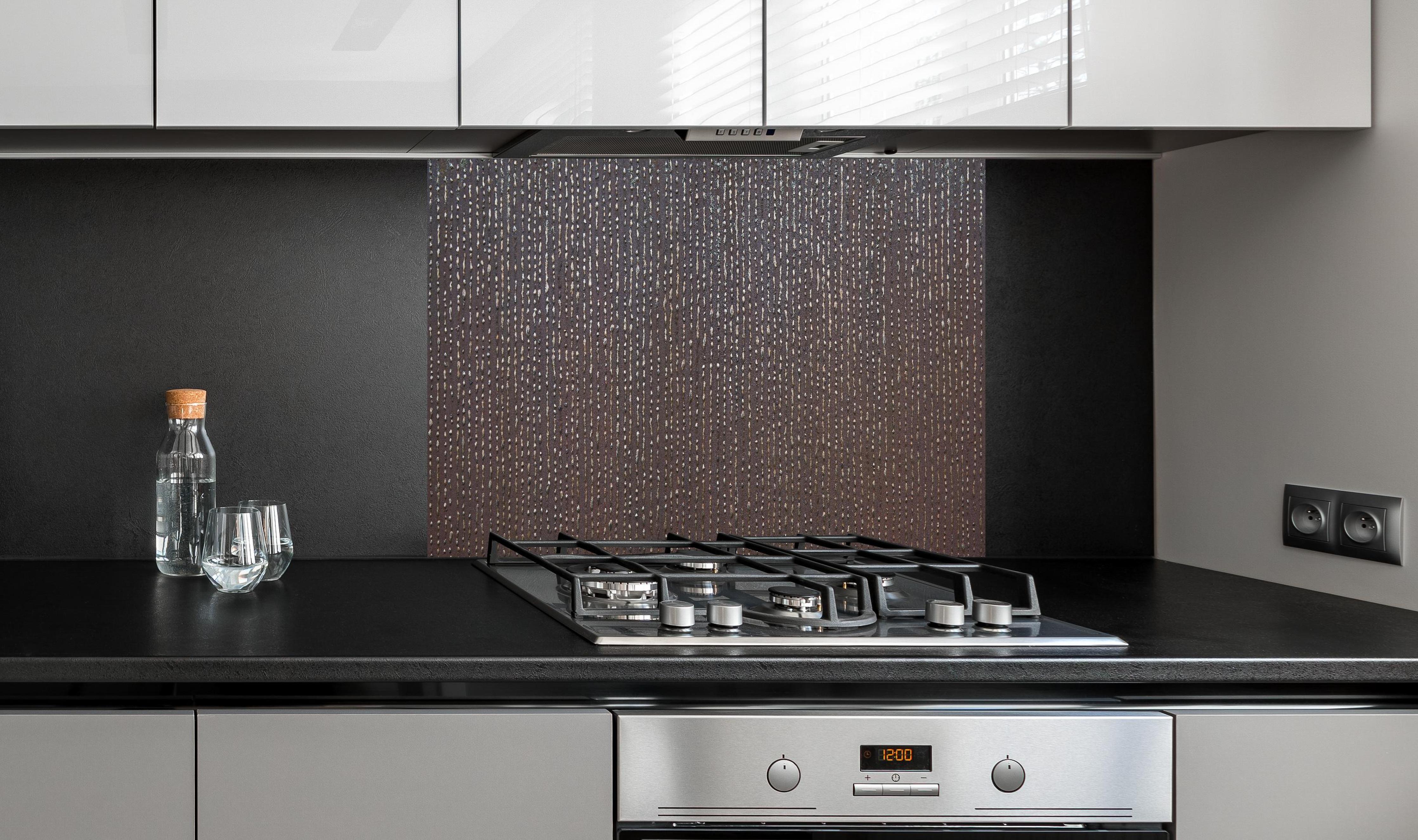 Spritzschutz - Ungewöhnliche Tropfenstruktur hinter einem Cerankochfeld zwischen Holz-Kochutensilien