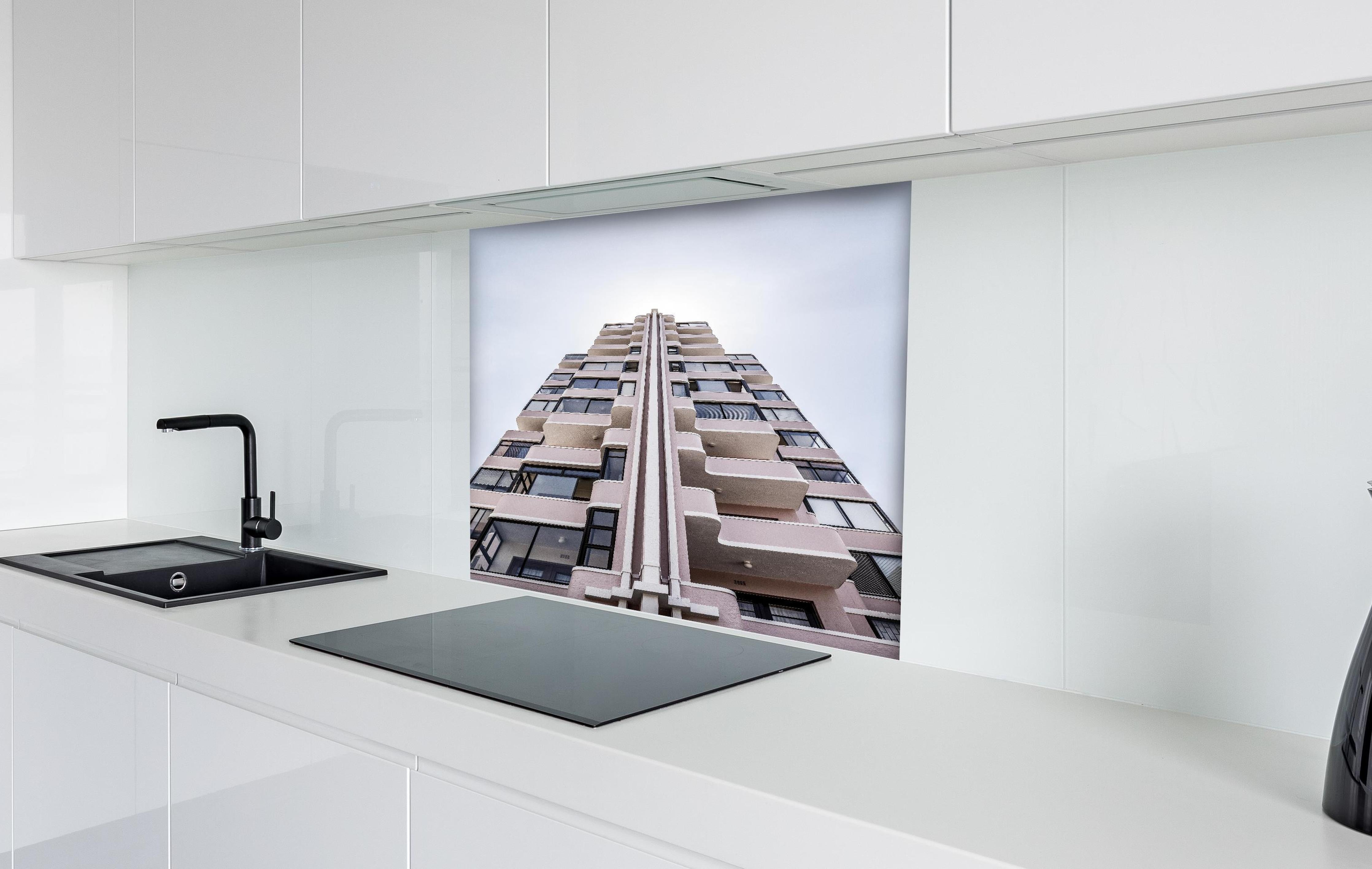 Spritzschutz - Urbanes Hochhaus mit grau-beigen Akzenten hinter einem Cerankochfeld zwischen Holz-Kochutensilien
