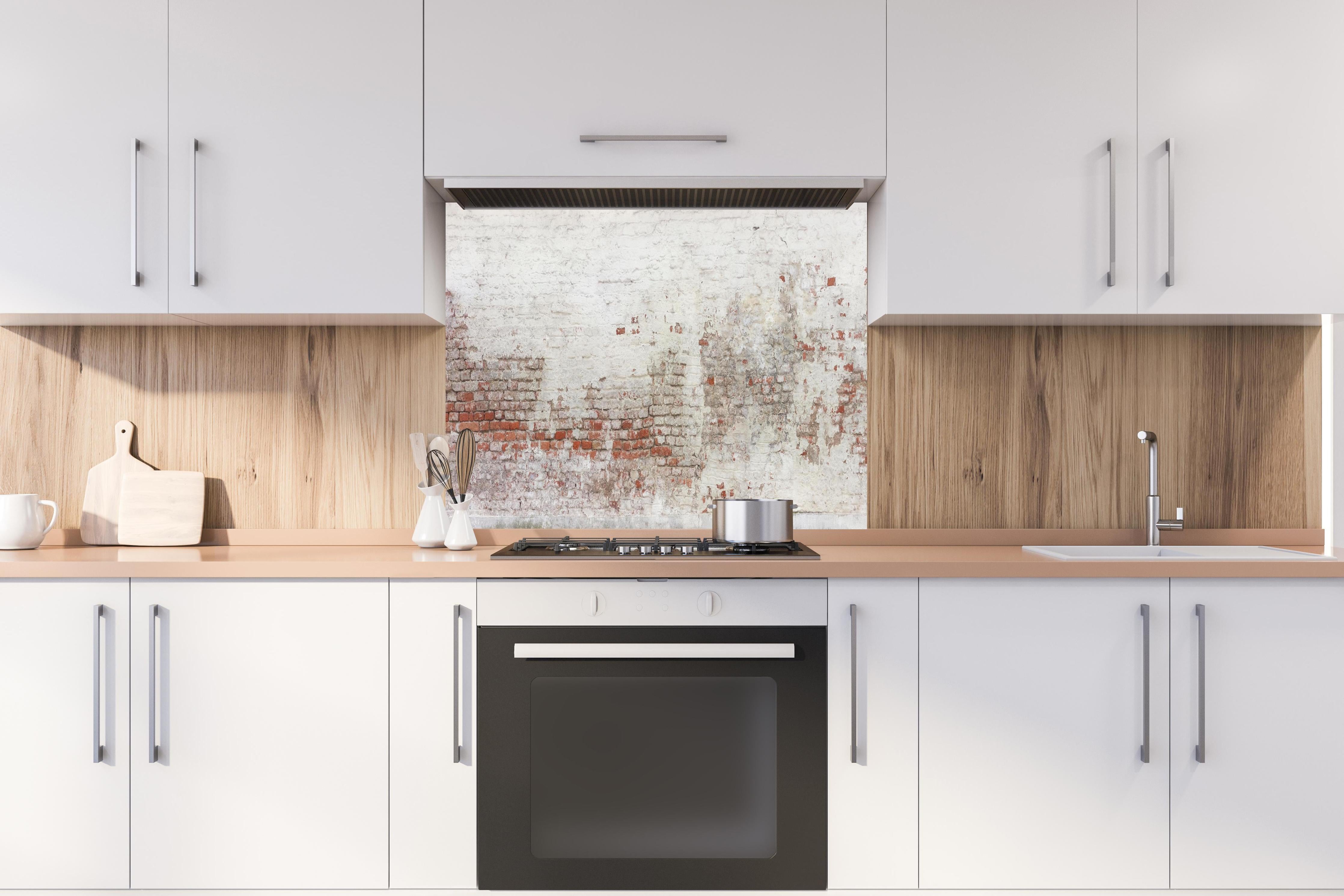 Spritzschutz - Veraltete Hauswand hinter einem Cerankochfeld zwischen Holz-Kochutensilien