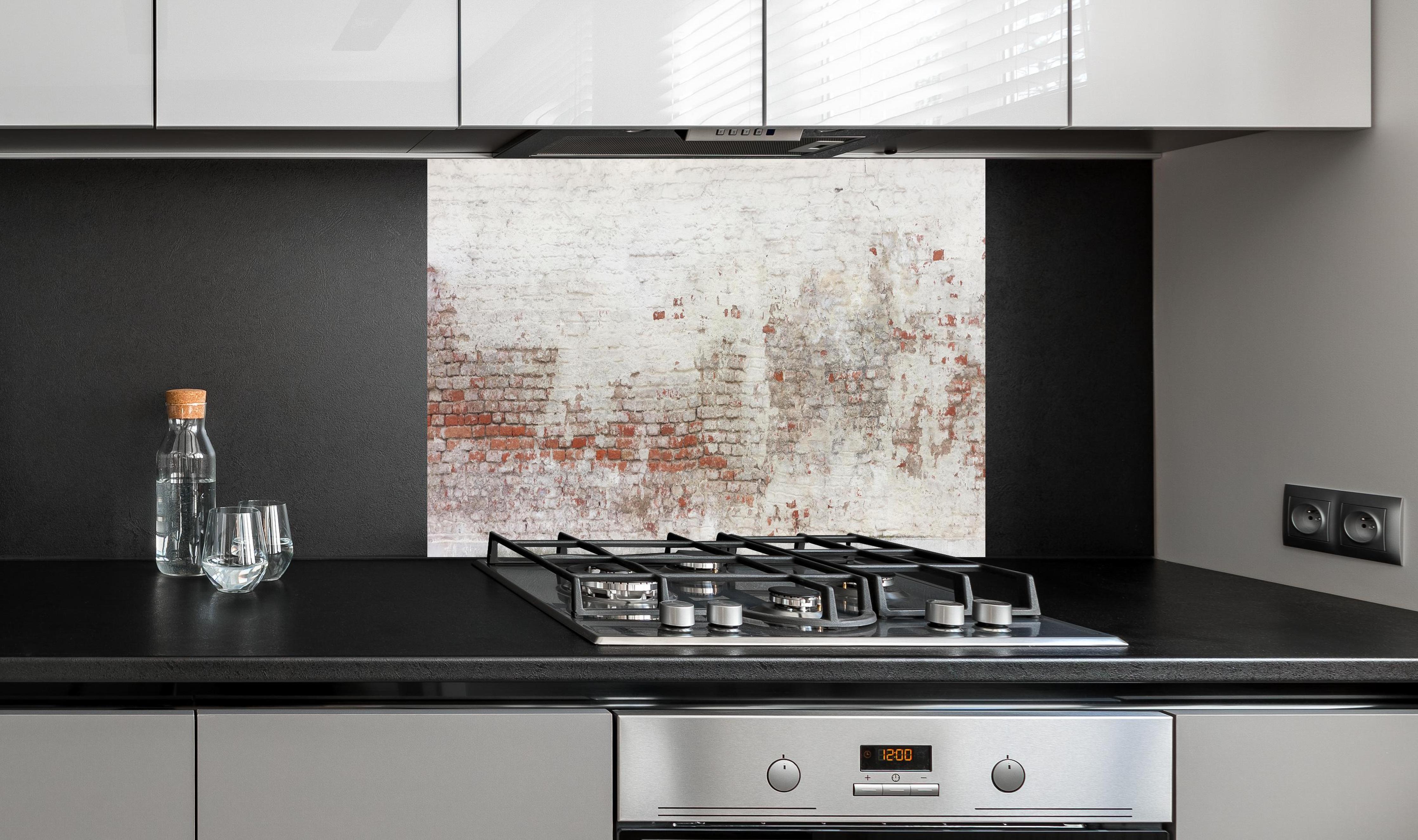 Spritzschutz - Veraltete Hauswand hinter einem Cerankochfeld zwischen Holz-Kochutensilien