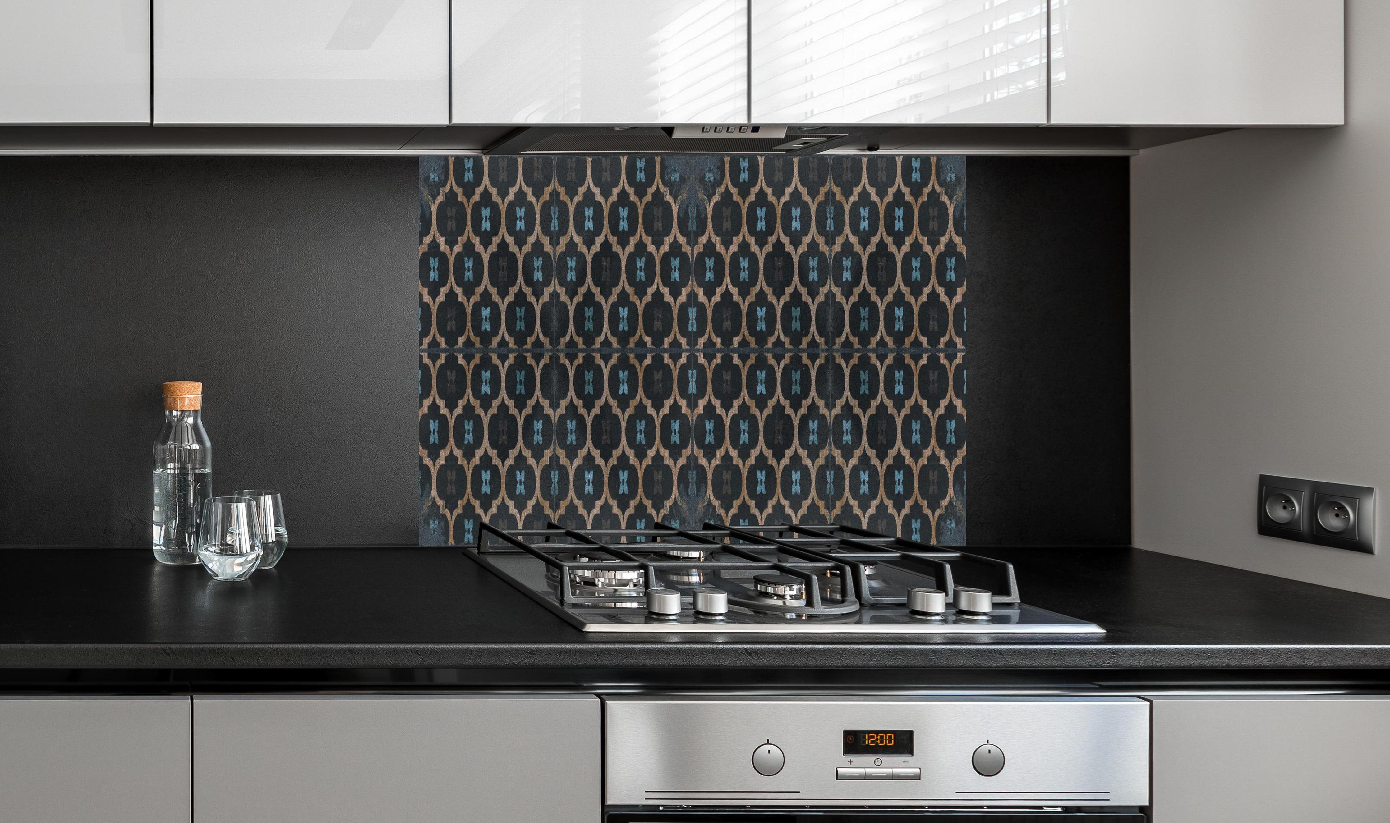 Spritzschutz - Veraltete künstlerische Fliesen hinter einem Cerankochfeld zwischen Holz-Kochutensilien