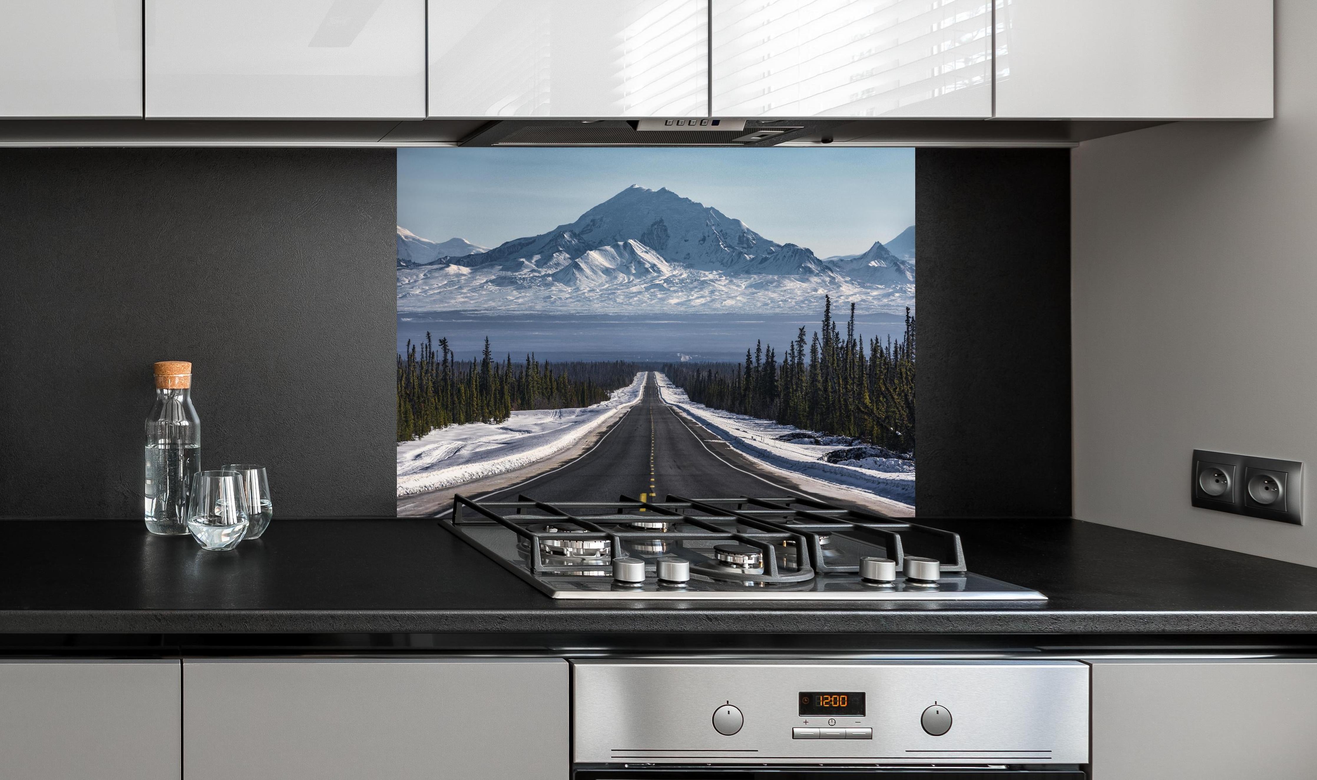 Spritzschutz - Verschneite Alpenstraße Alaska in Winterlandschaft hinter einem Cerankochfeld zwischen Holz-Kochutensilien