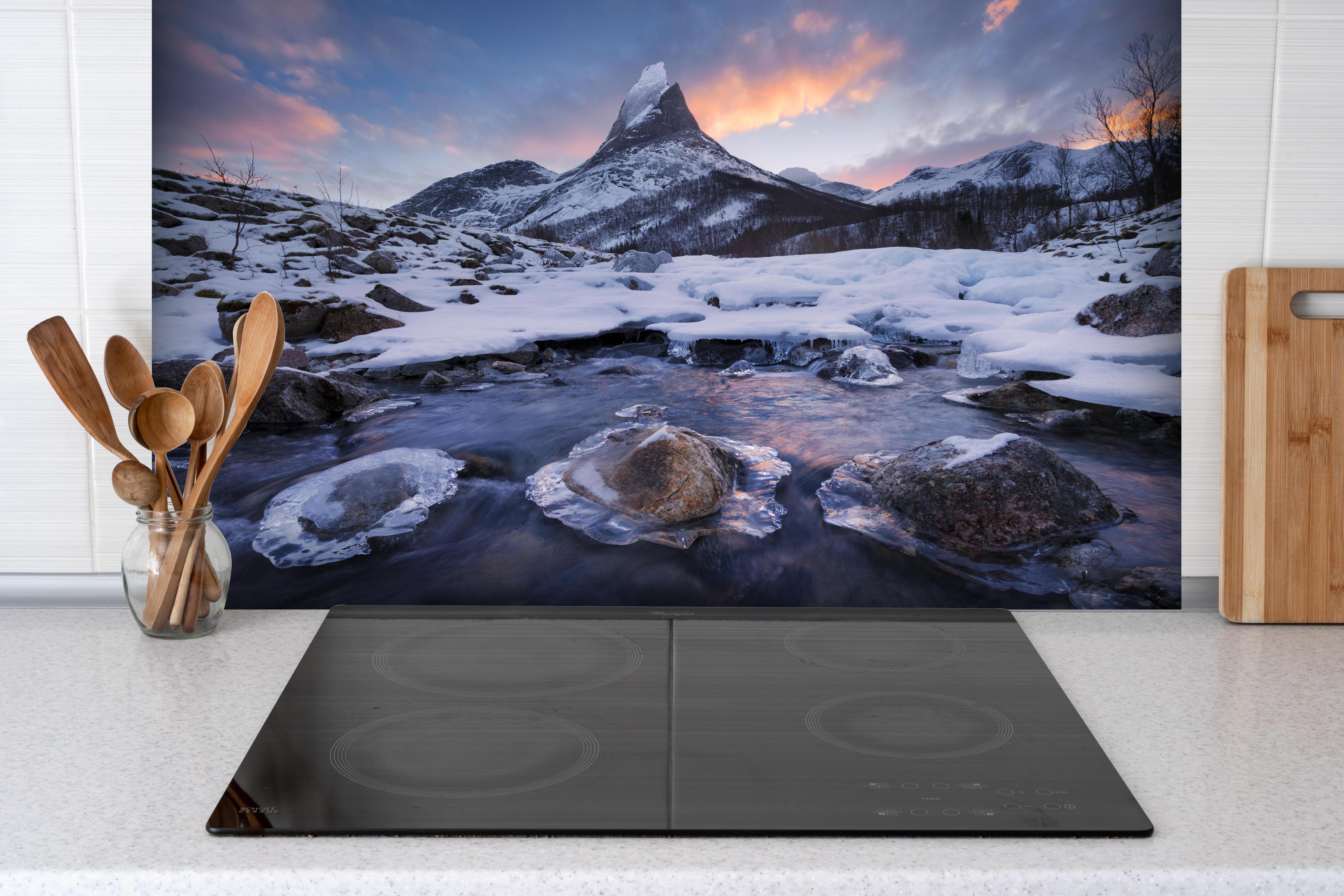 Spritzschutz - Verschneiter Gipfel Stetind im Abendlicht hinter einem Cerankochfeld zwischen Holz-Kochutensilien