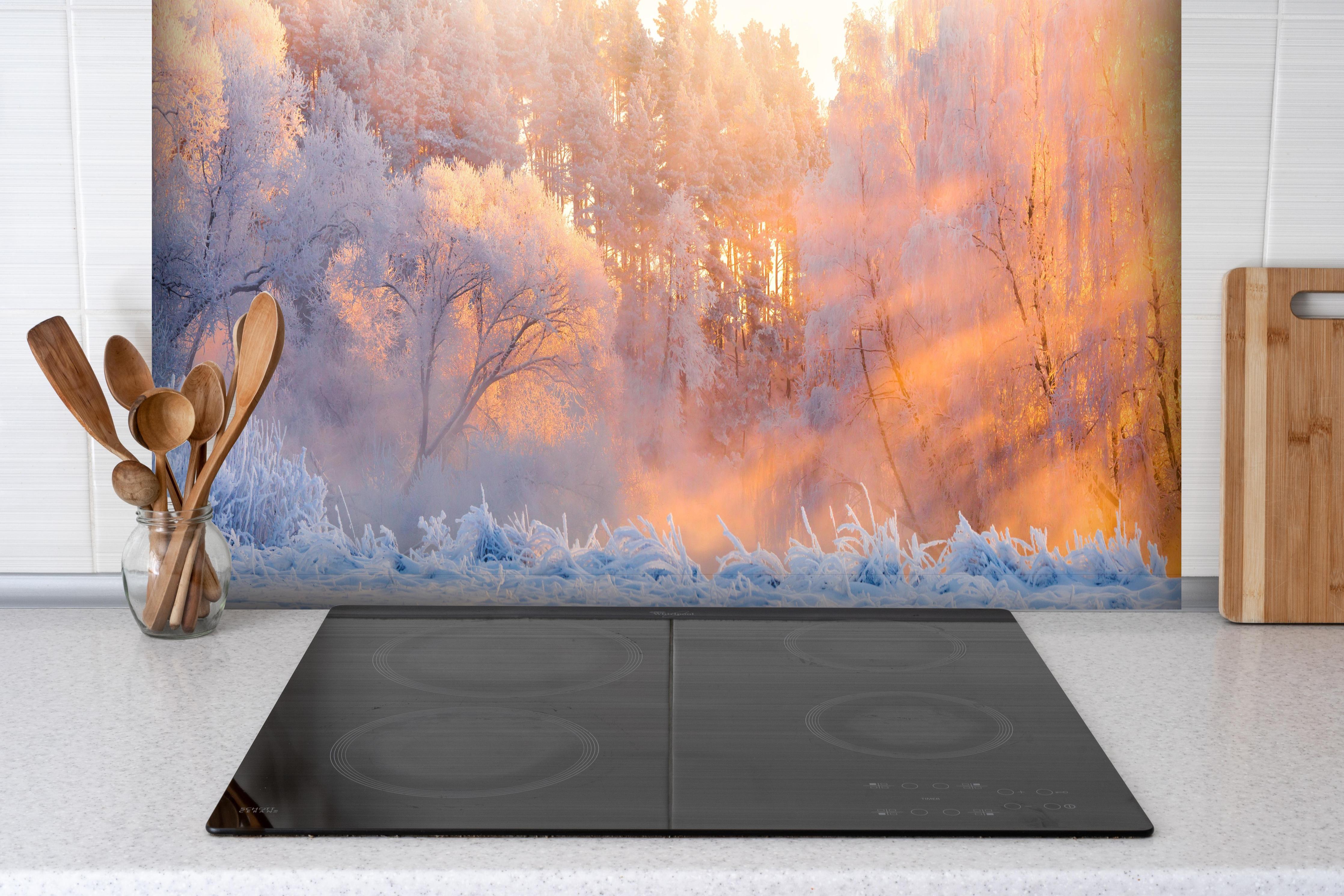 Spritzschutz - Verschneiter Wald im goldenen Morgenlicht hinter einem Cerankochfeld zwischen Holz-Kochutensilien
