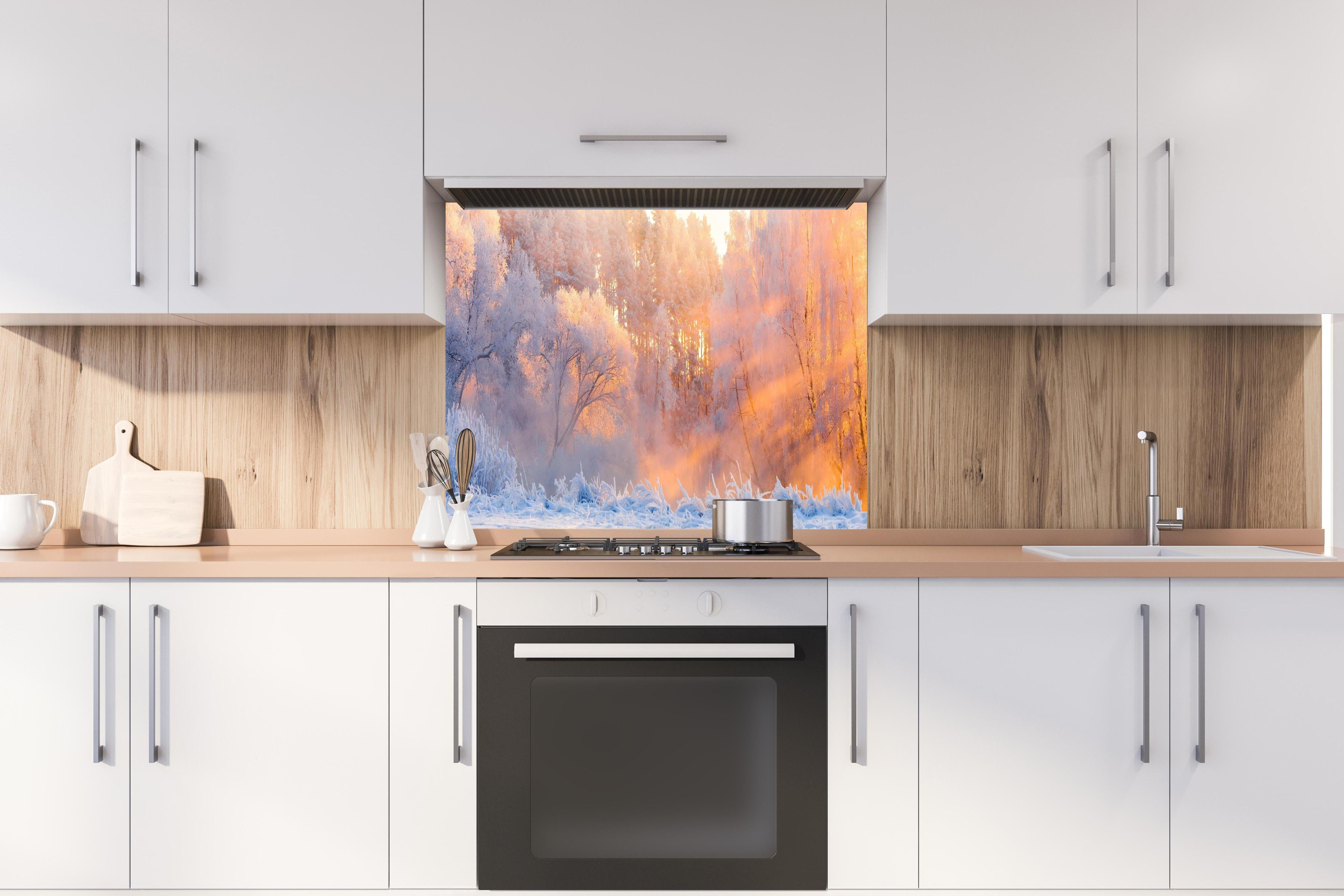 Spritzschutz - Verschneiter Wald im goldenen Morgenlicht hinter einem Cerankochfeld zwischen Holz-Kochutensilien