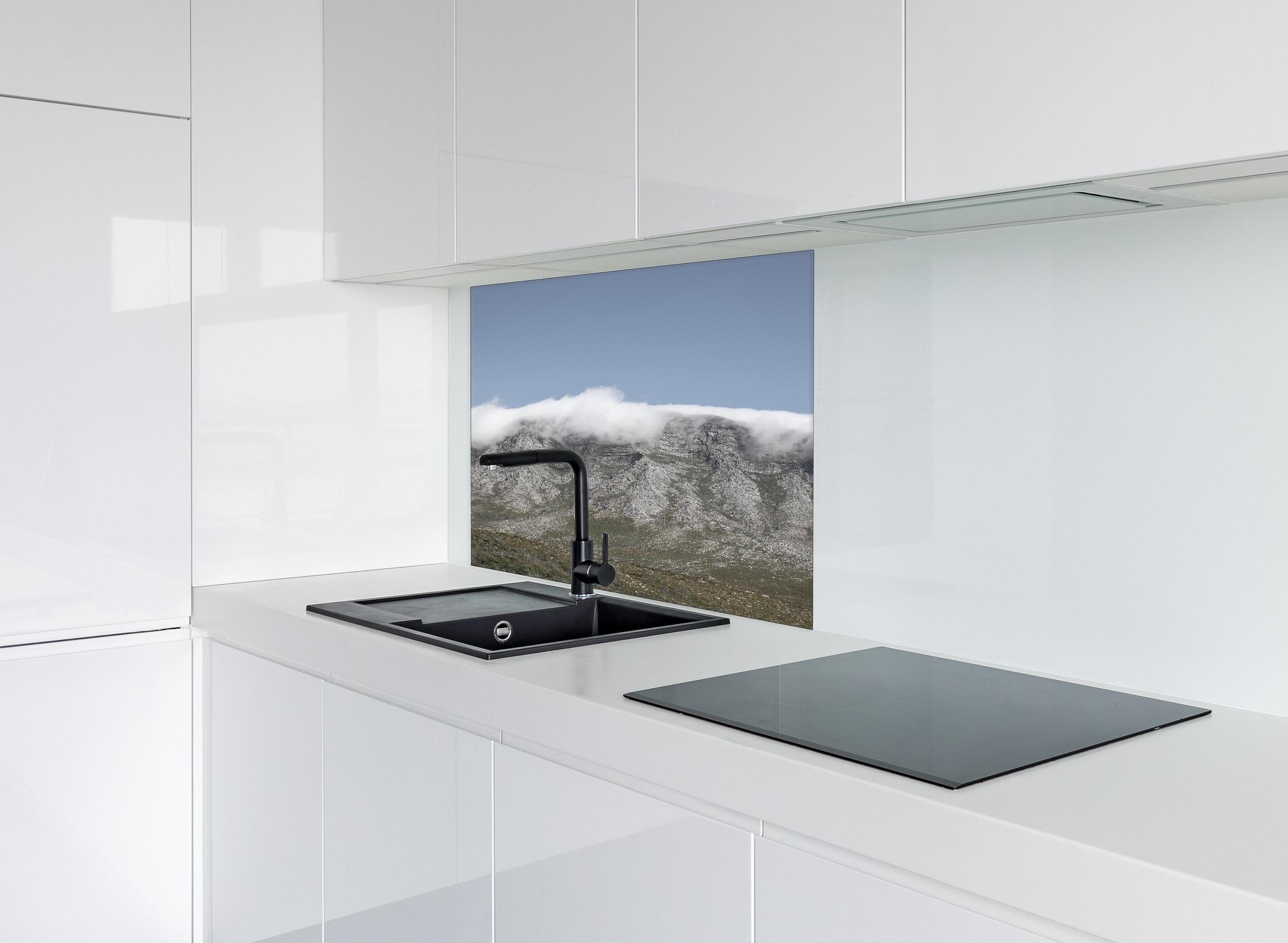 Spritzschutz - Verträumte Berglandschaft mit Wolkenverhang hinter einem Cerankochfeld zwischen Holz-Kochutensilien